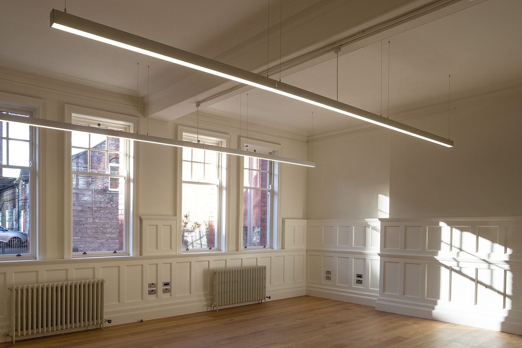 An empty room with a lot of windows and a wooden floor.