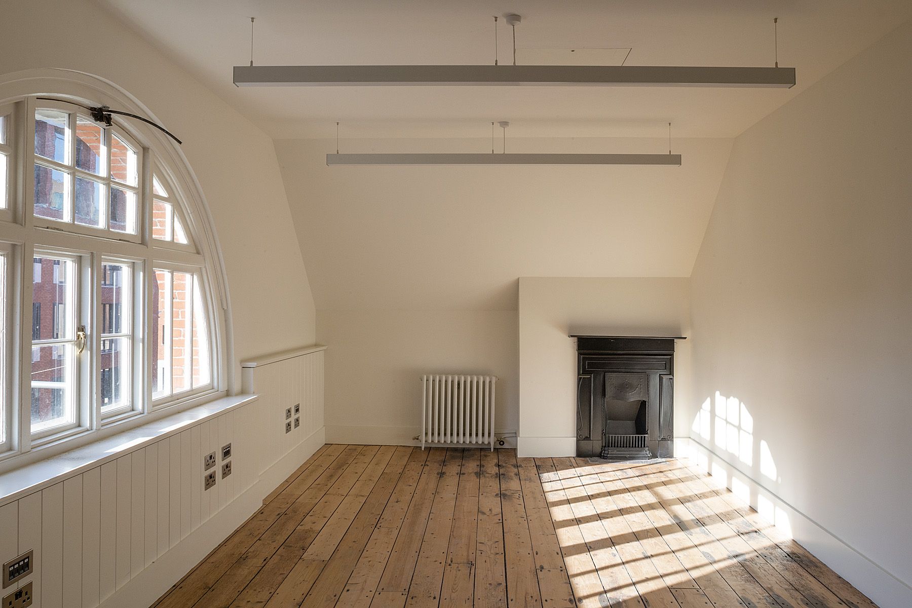 An empty room with wooden floors and a fireplace.