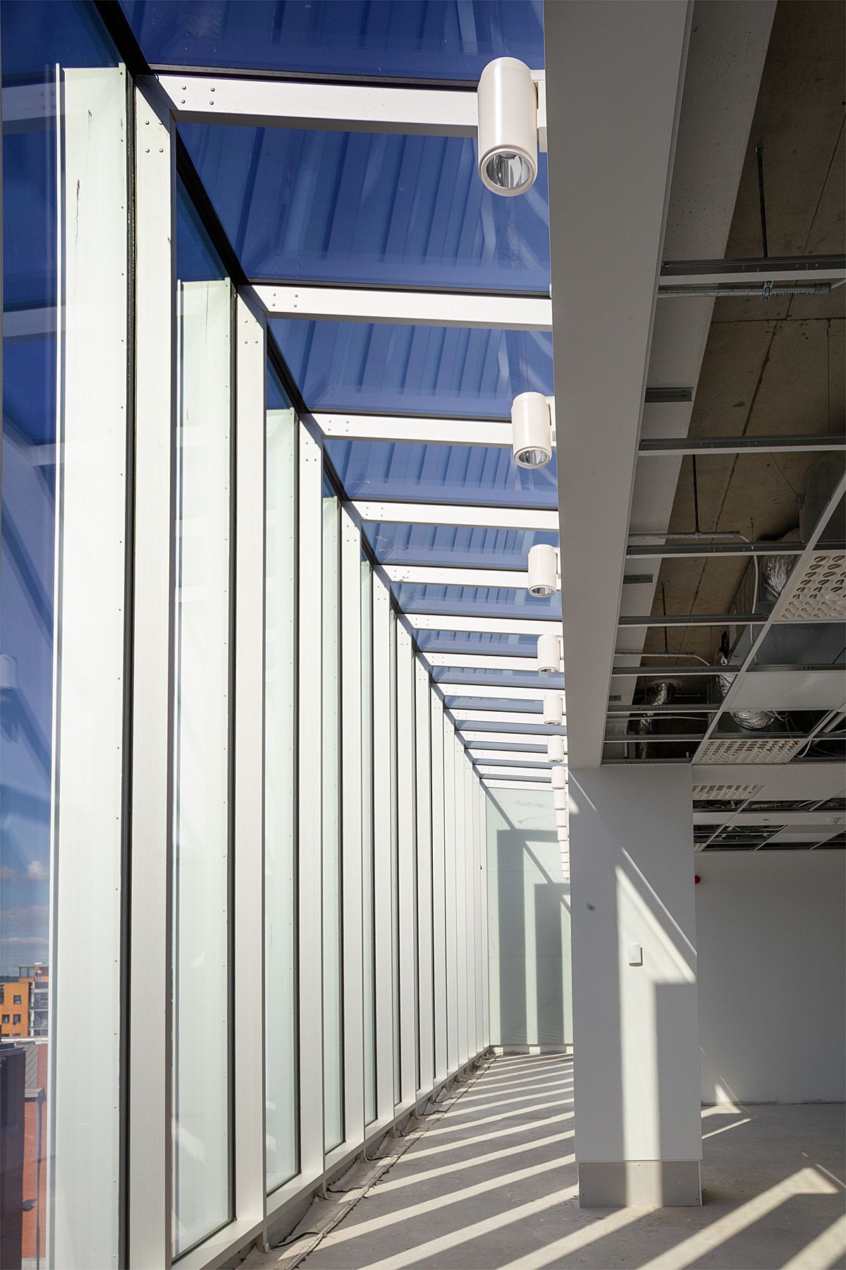 A long hallway with a lot of windows and a blue sky in the background.