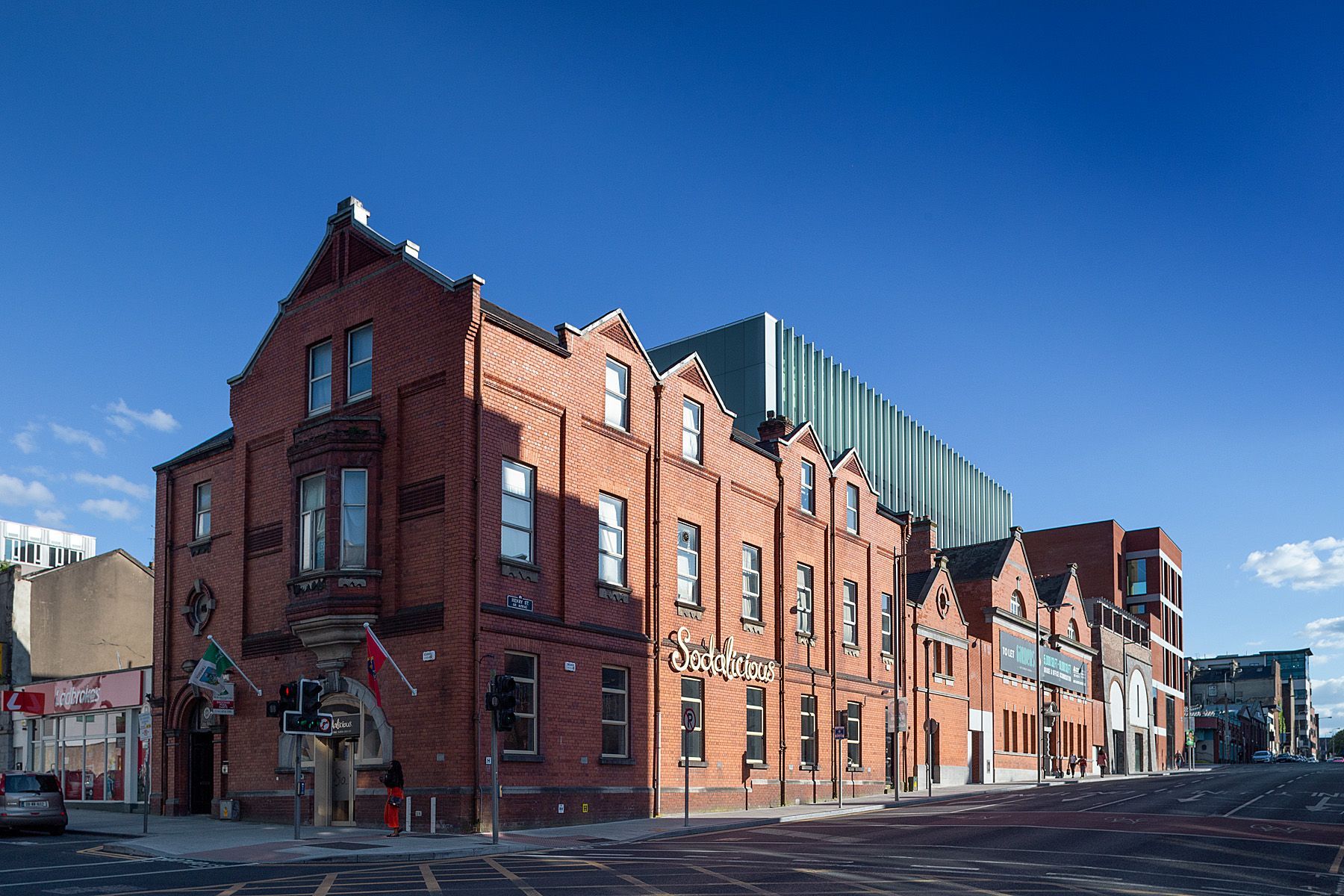 A large red brick building is sitting on the corner of a city street.
