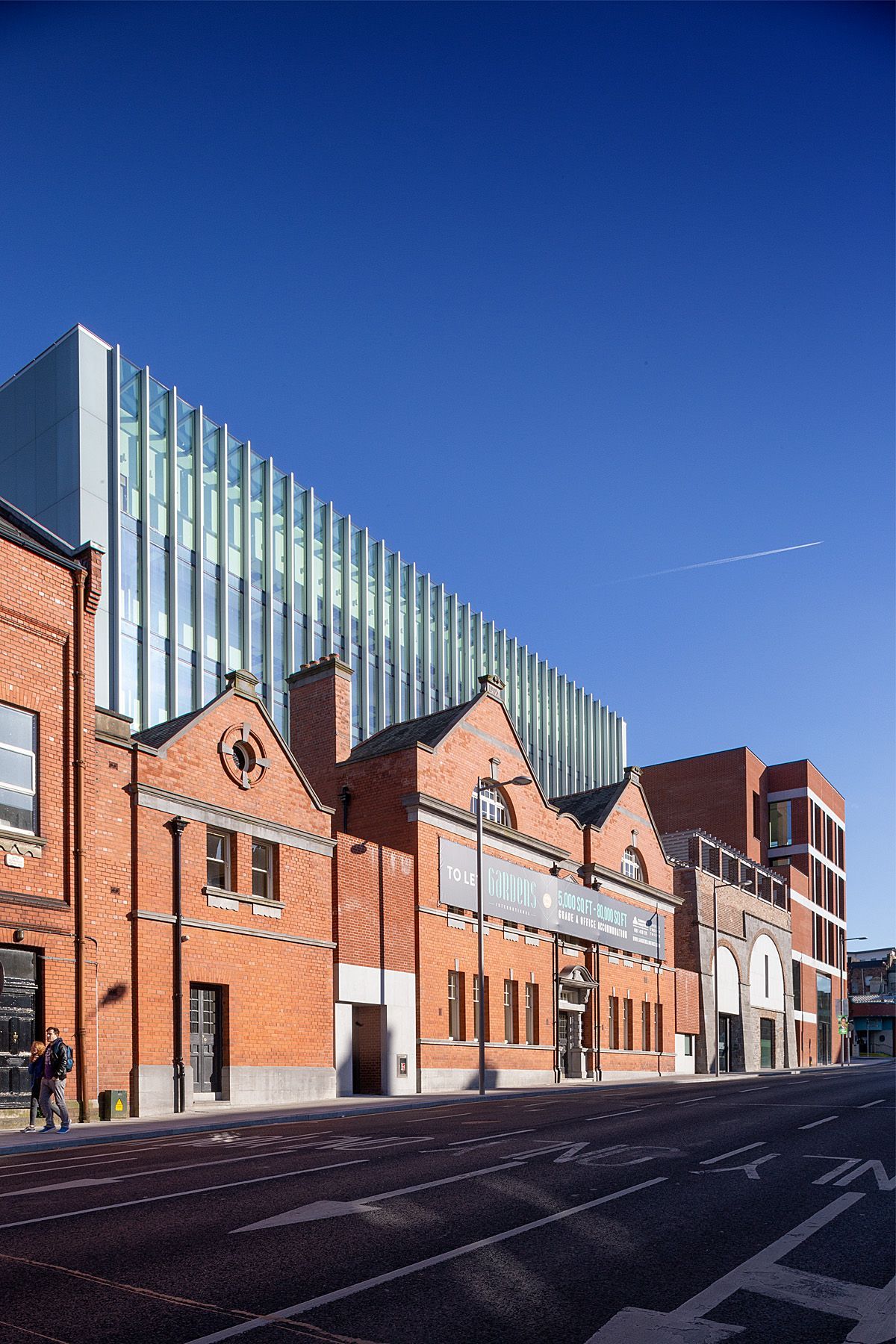 A large building with a lot of windows is next to a brick building