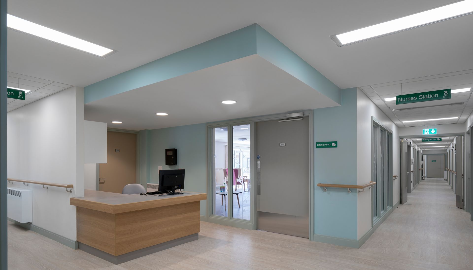 A long hallway in a hospital with a desk and a computer.