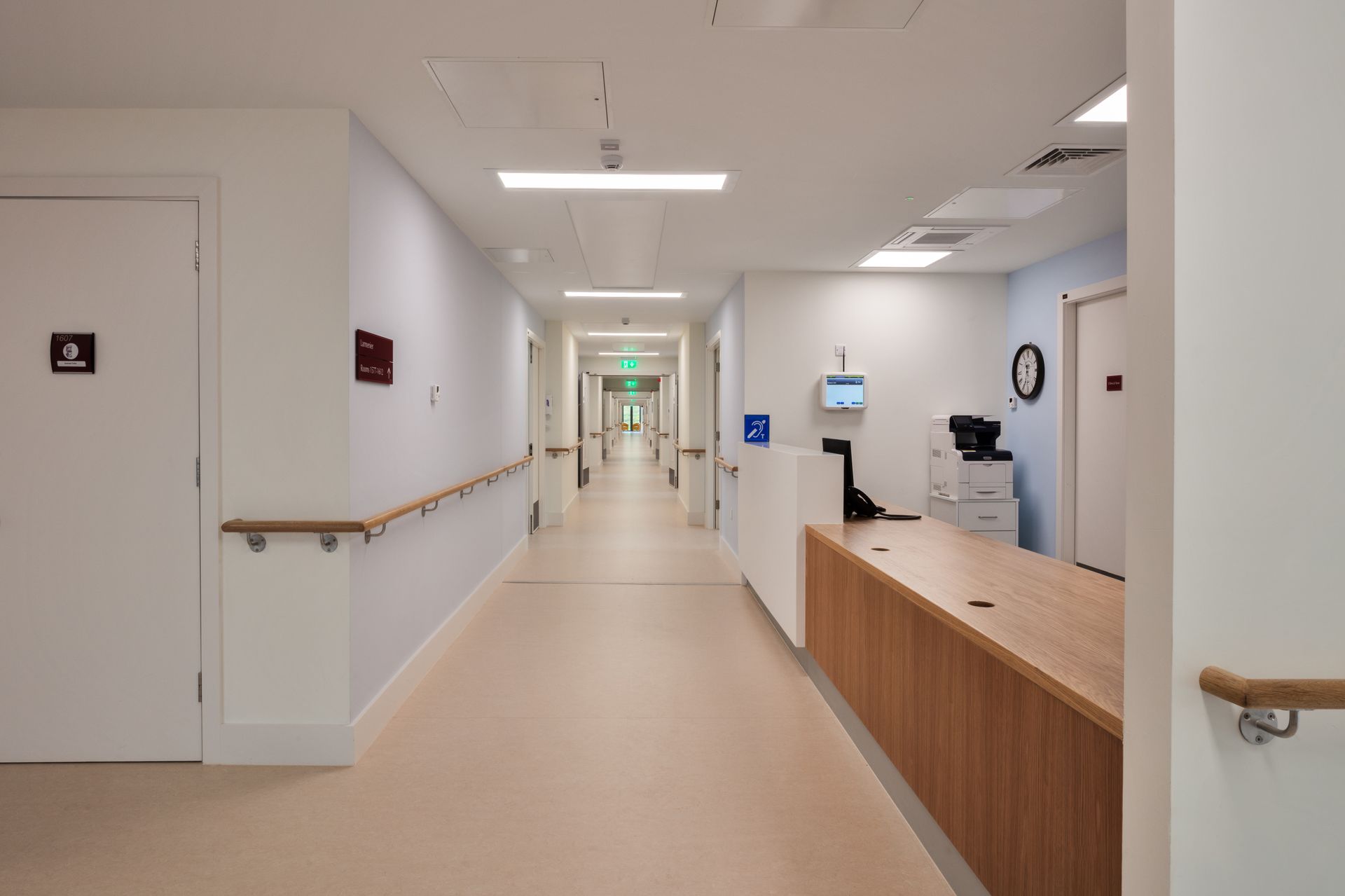 A long hallway in a hospital with a counter in the middle.