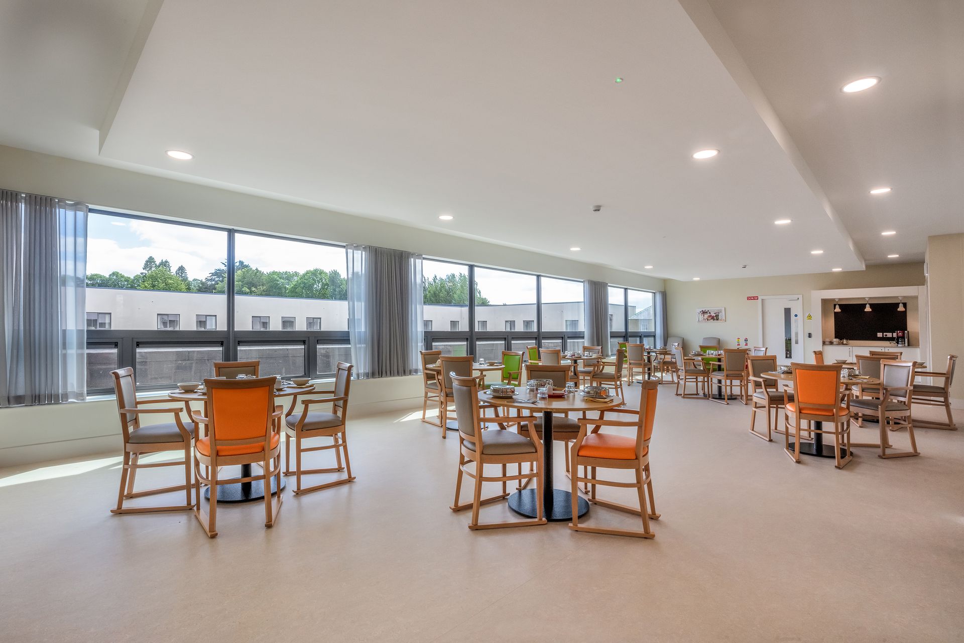 A large dining room with tables and chairs and lots of windows.