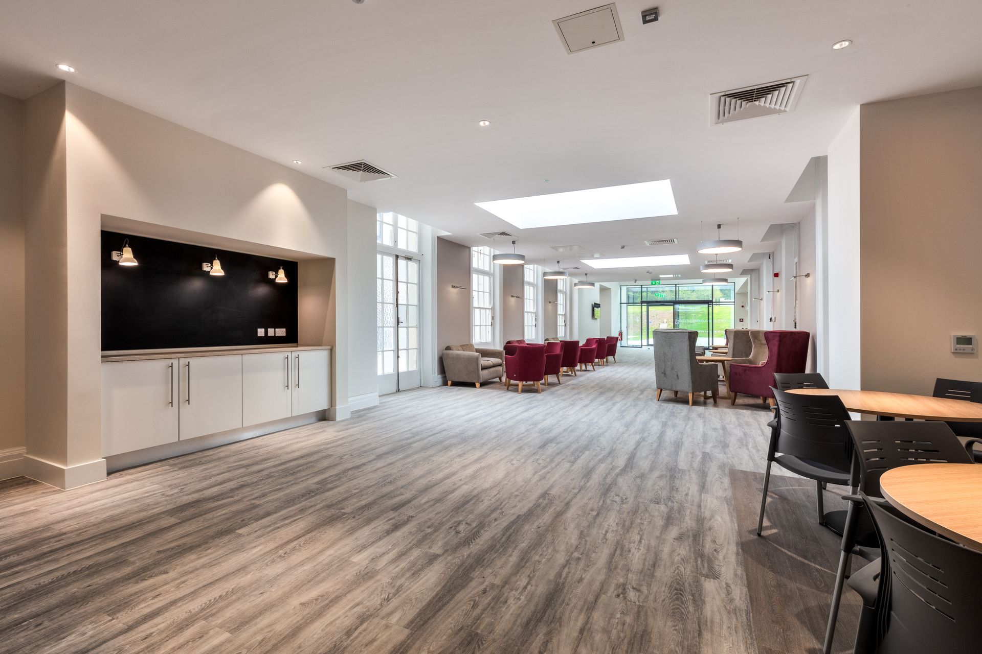 A large room with wooden floors and tables and chairs.