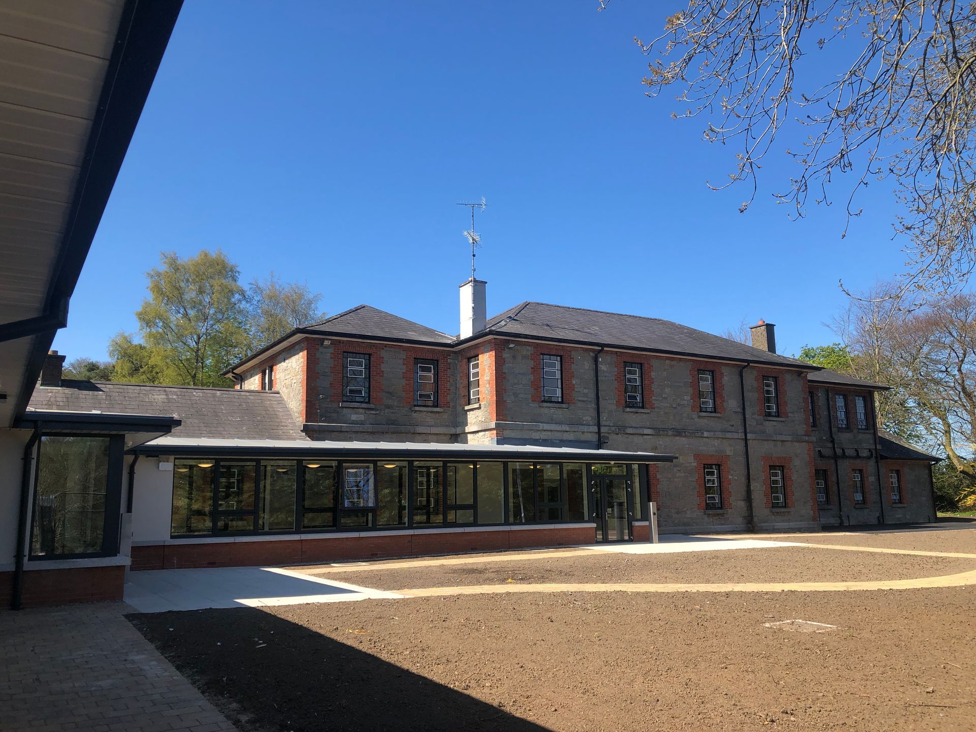 A large brick building with a lot of windows and a lot of dirt in front of it.