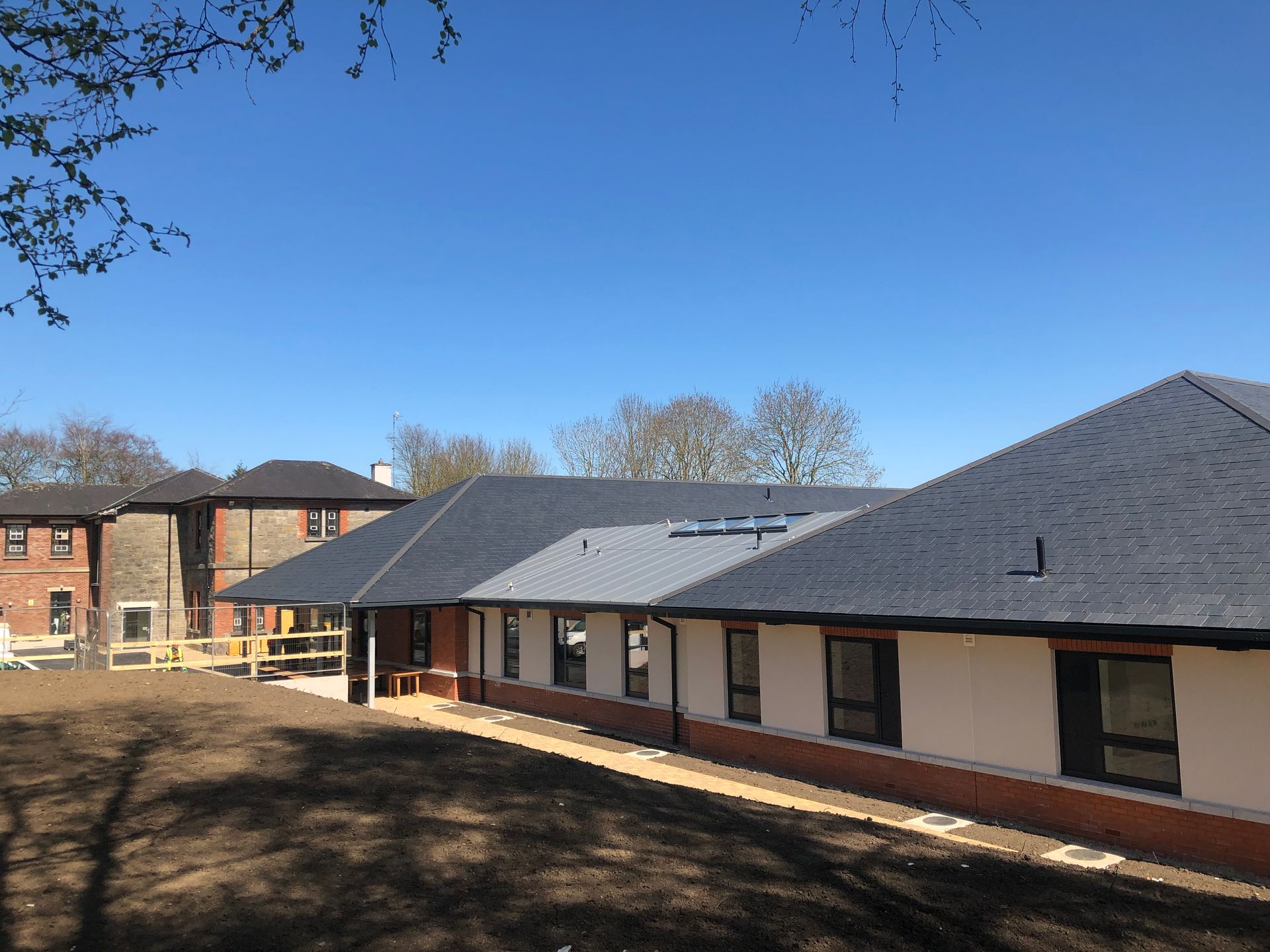 A large house with a slate roof and a brick building in the background.