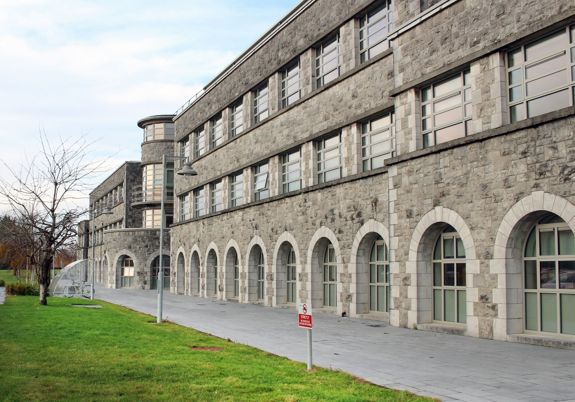 A large stone building with arched windows and a no parking sign in front of it