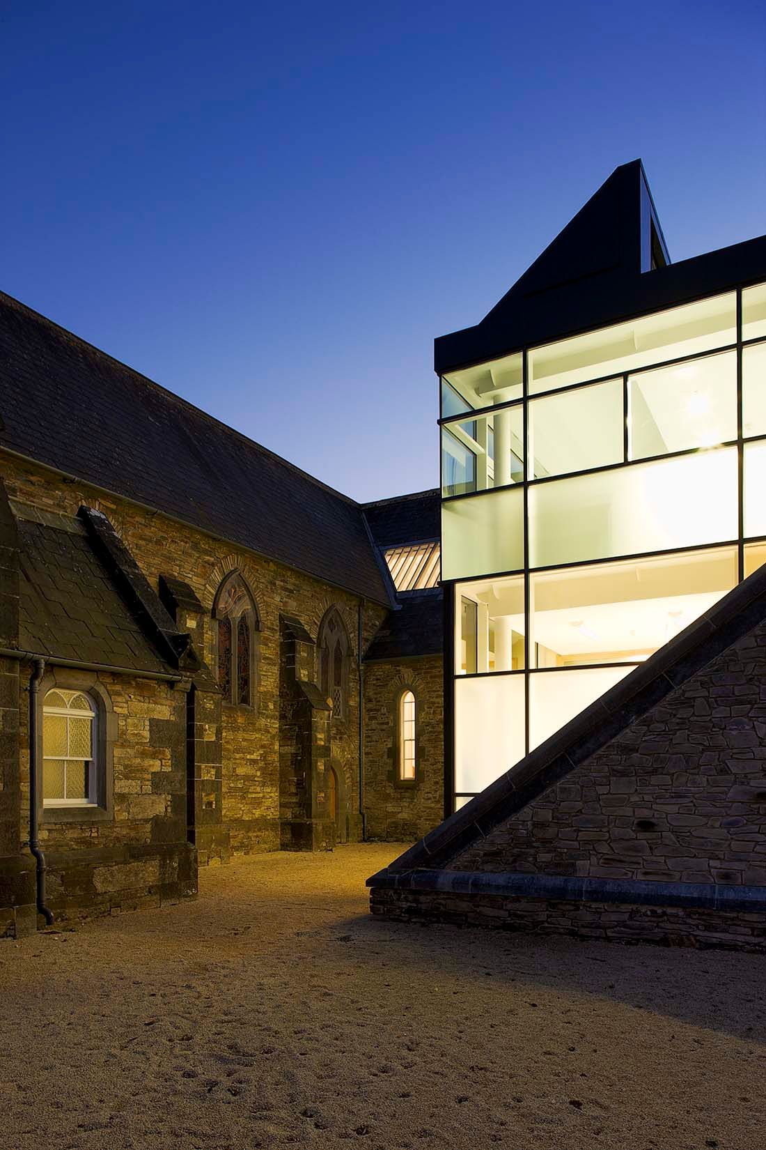 A large building with a lot of windows is next to a smaller building