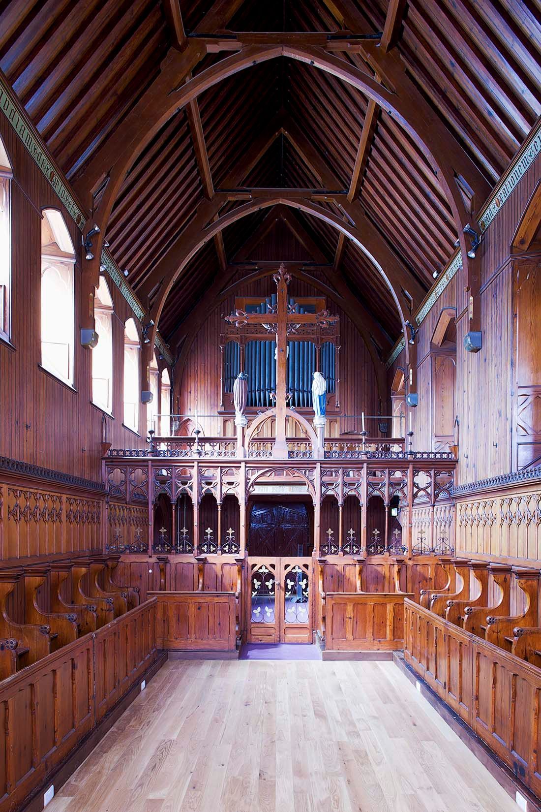 The inside of a wooden church with a cross on the ceiling