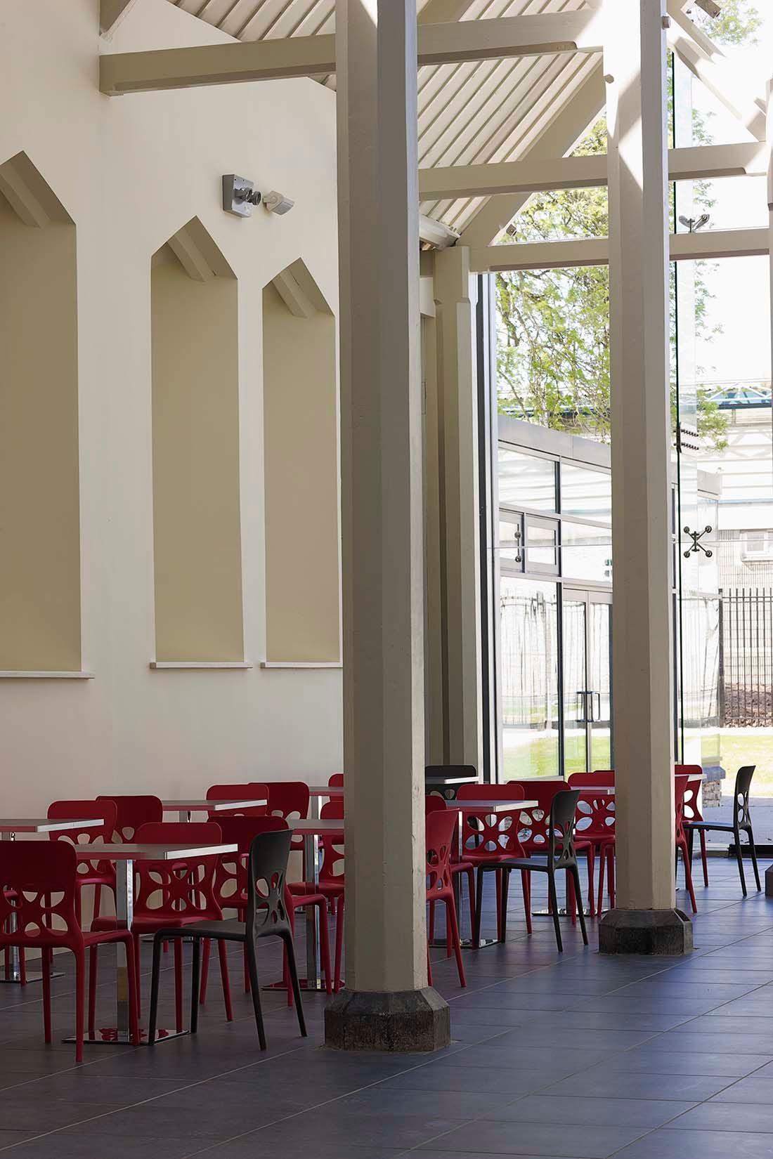 A row of tables and chairs in a room with columns
