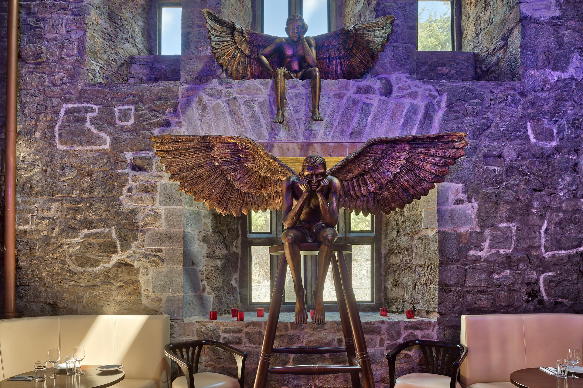 A statue of a man with wings is sitting on a ladder in a room.
