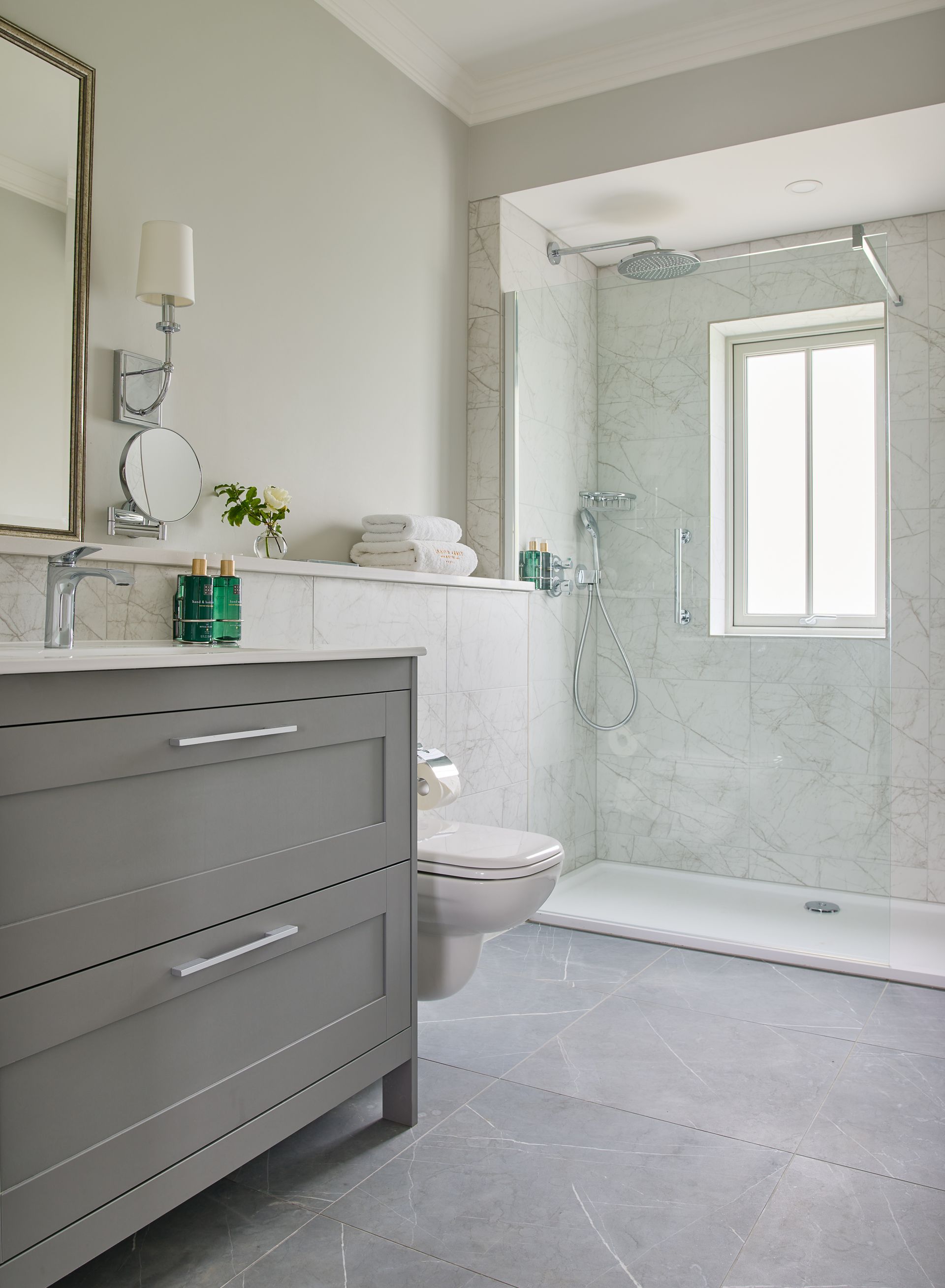A bathroom with a toilet , sink , mirror and walk in shower.