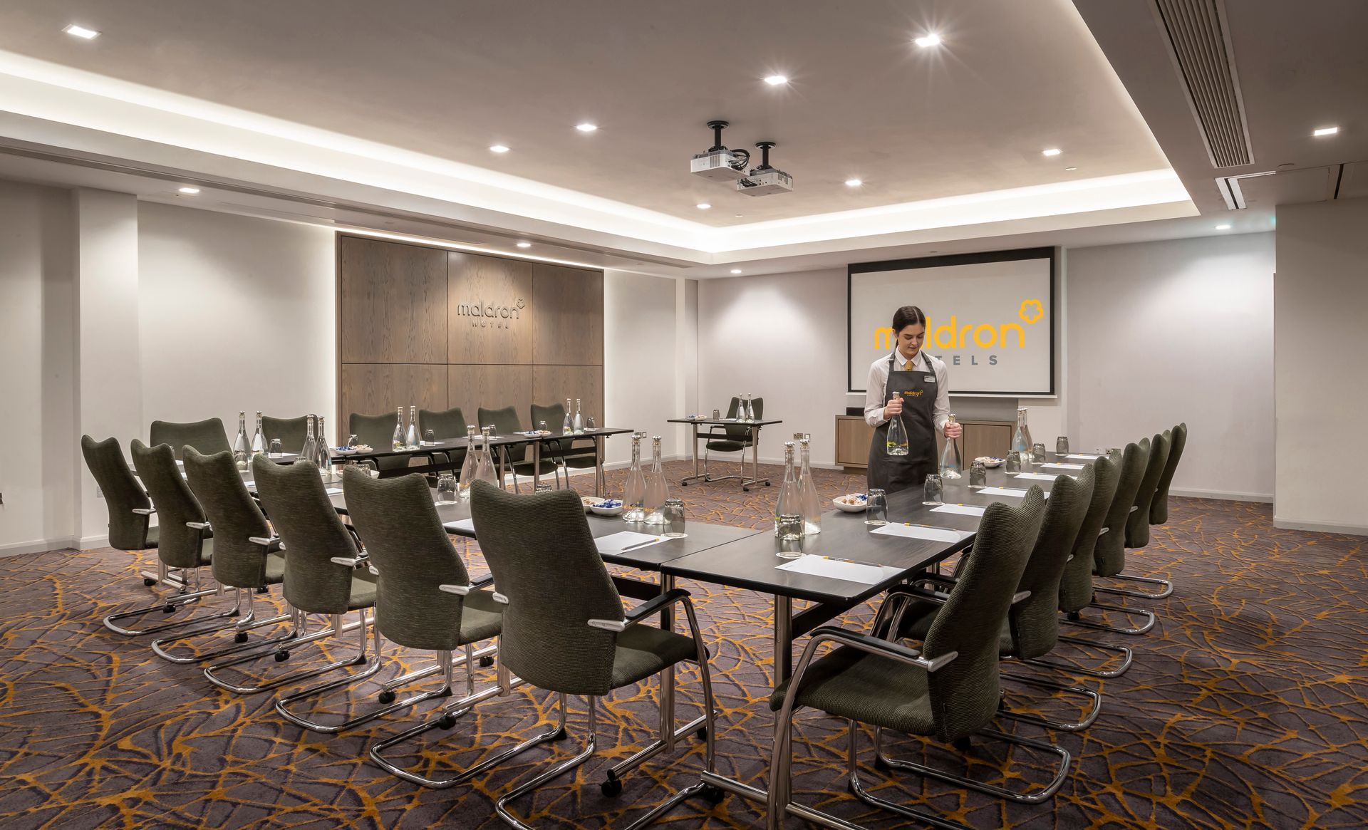 A man is standing in a conference room with a long table and chairs.