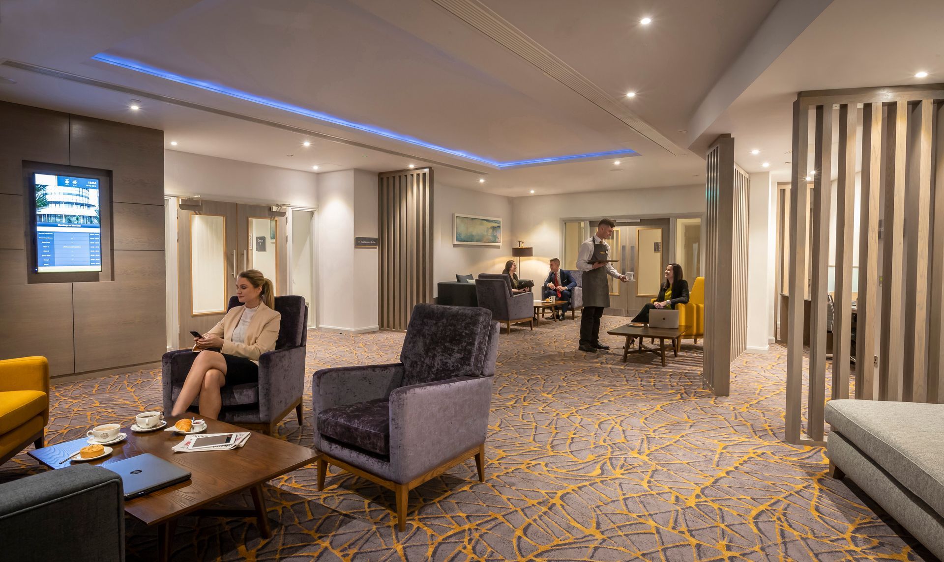 A woman is sitting in a chair in a lobby of a hotel.