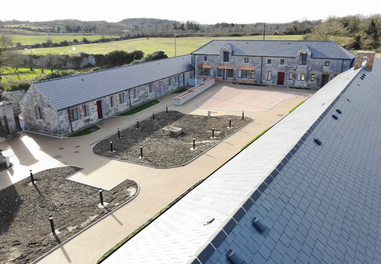 An aerial view of a large stone building with a slate roof