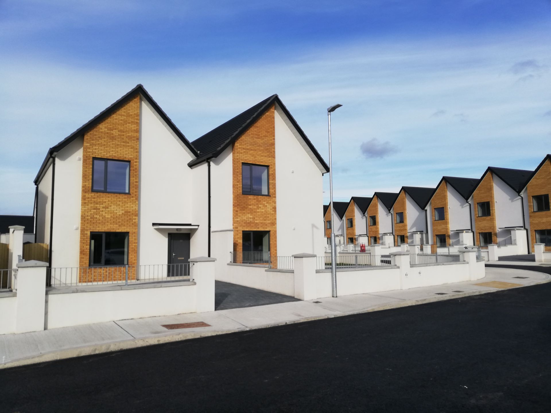 A row of houses on a street with a blue sky in the background