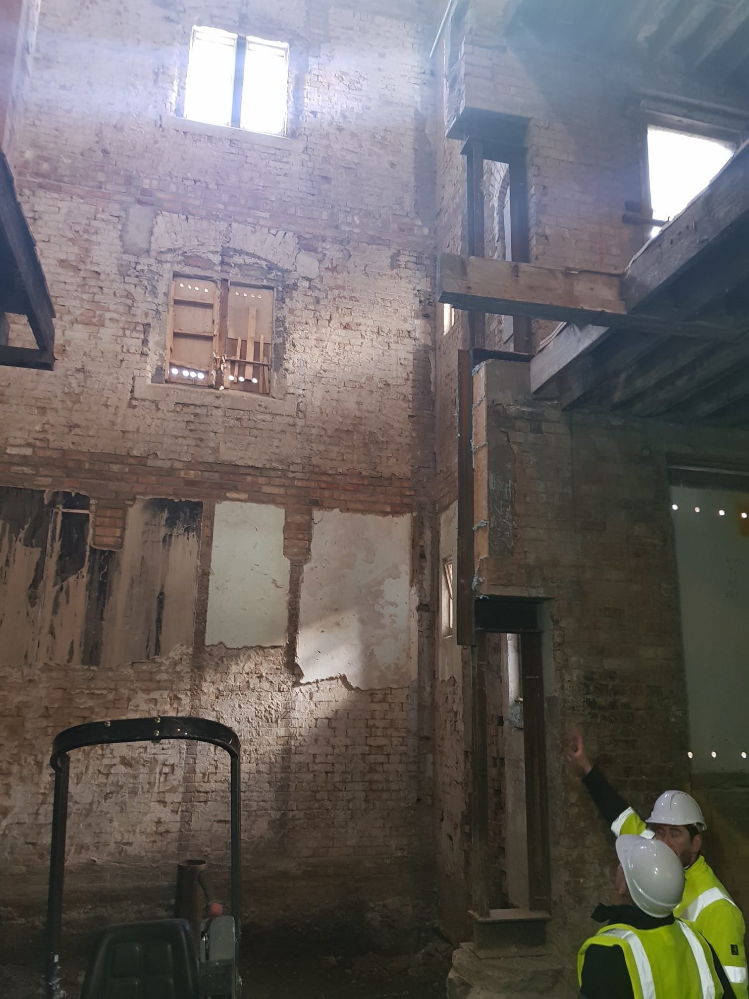 Two men are standing in an old building looking up at the ceiling.