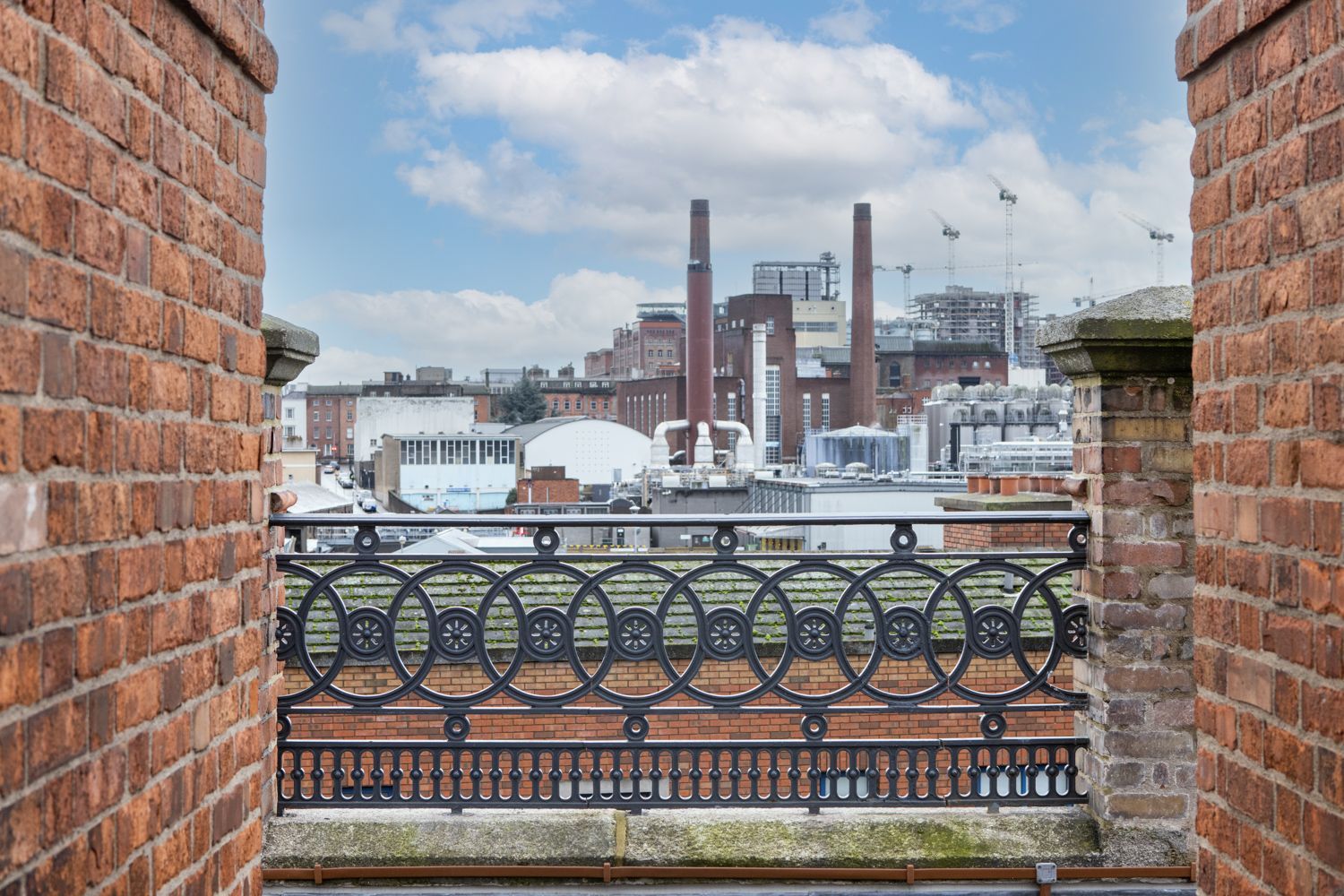 A view of a city from a balcony with a brick wall.