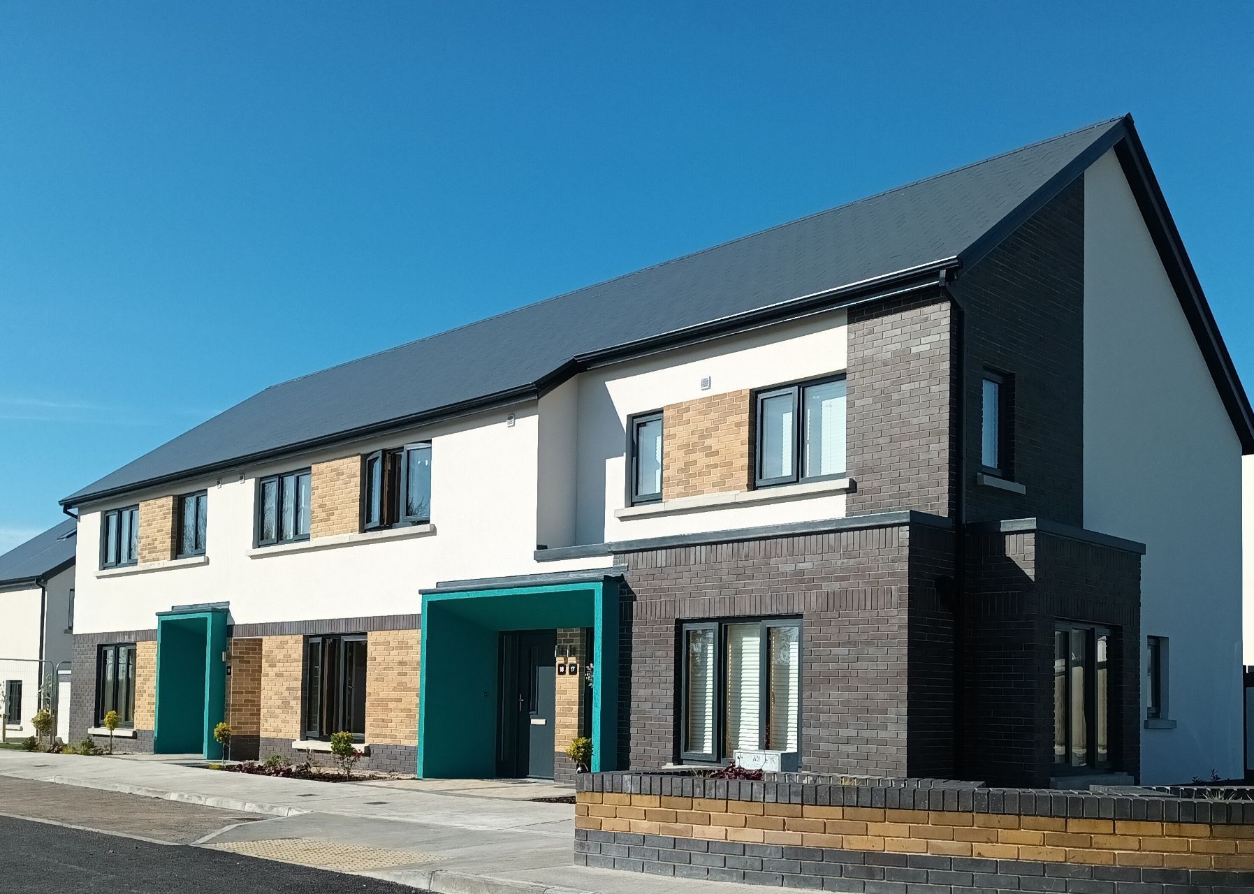 A white house with a black roof and a green awning