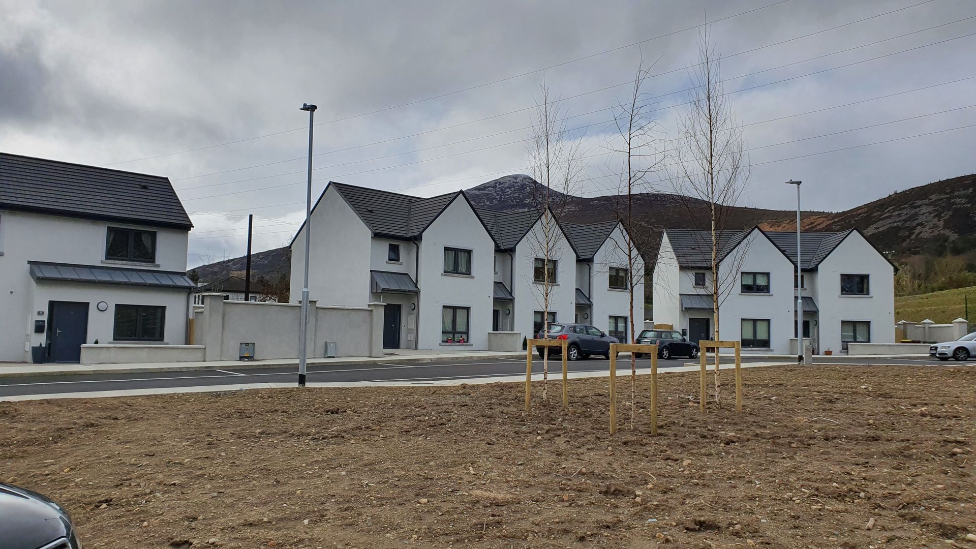 A row of white houses are sitting on top of a dirt field.