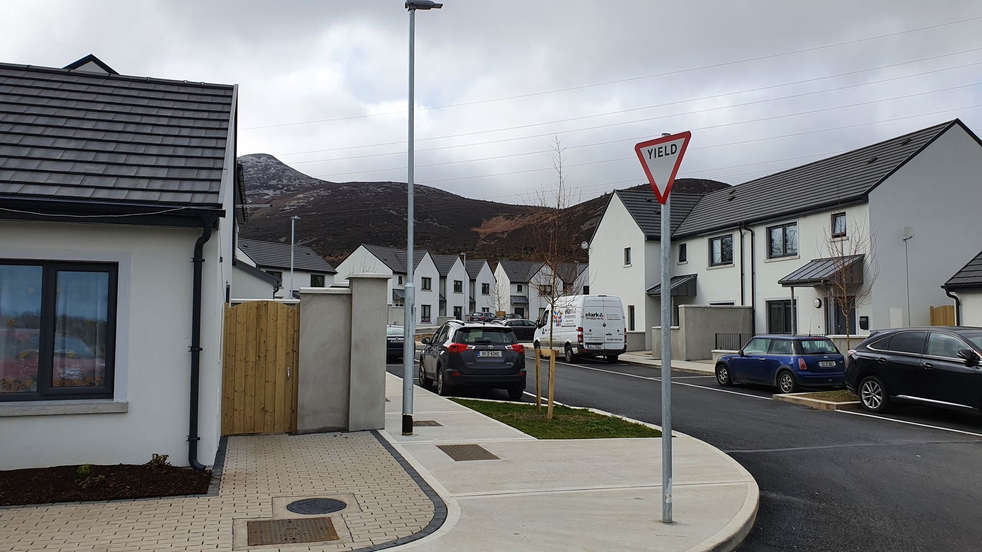 A row of white houses with cars parked on the side of the road.