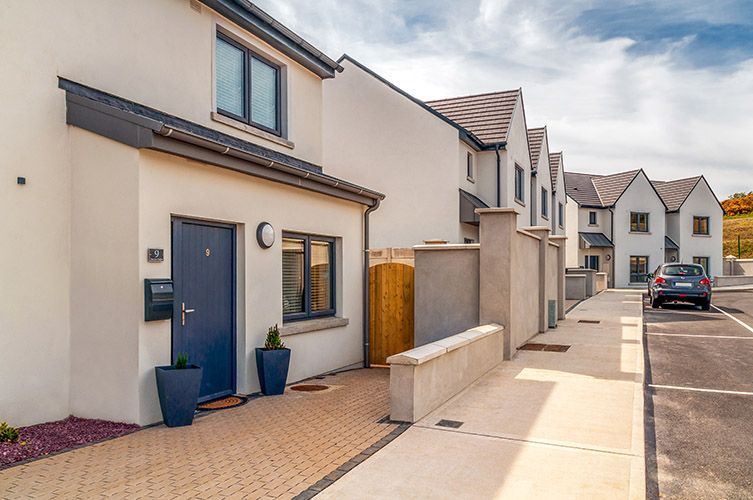 A white house with a blue door and a car parked in front of it.