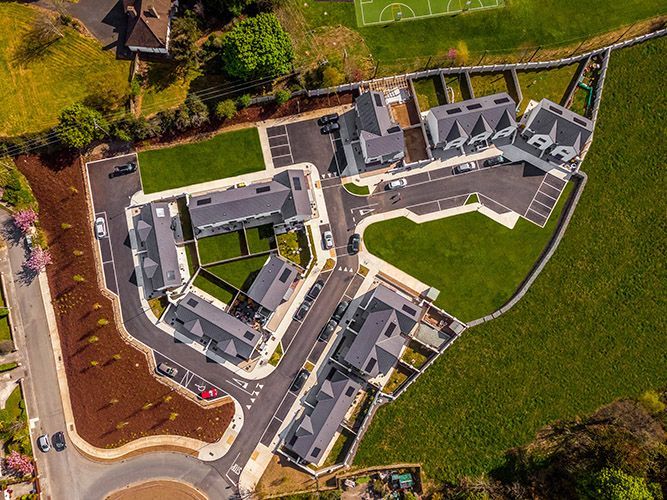 An aerial view of a residential area with a soccer field in the background.