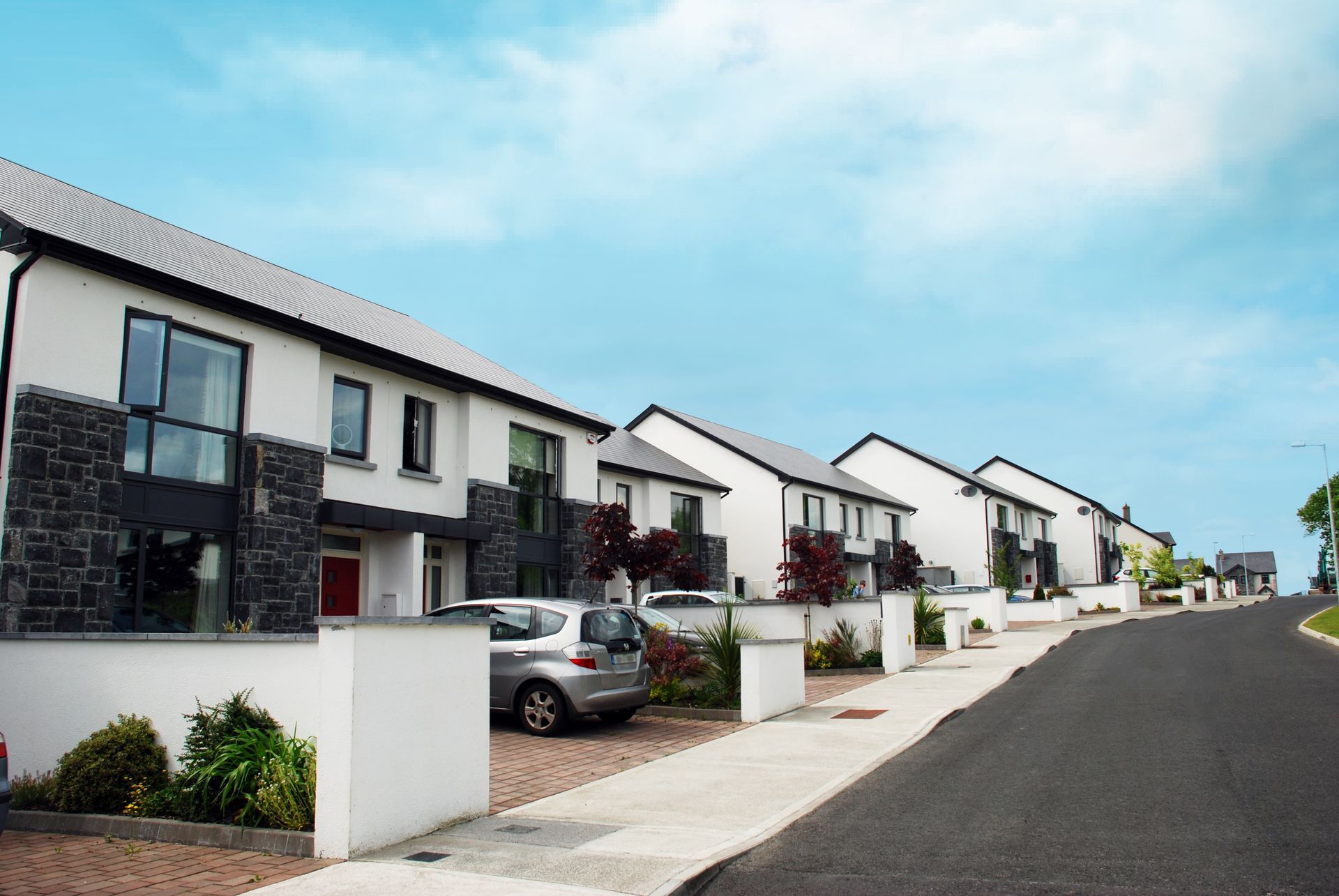 A row of houses with cars parked in front of them