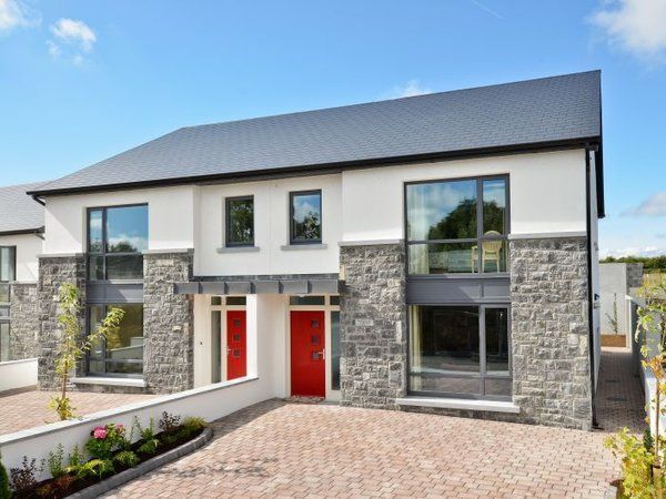 A white house with a black roof and red doors