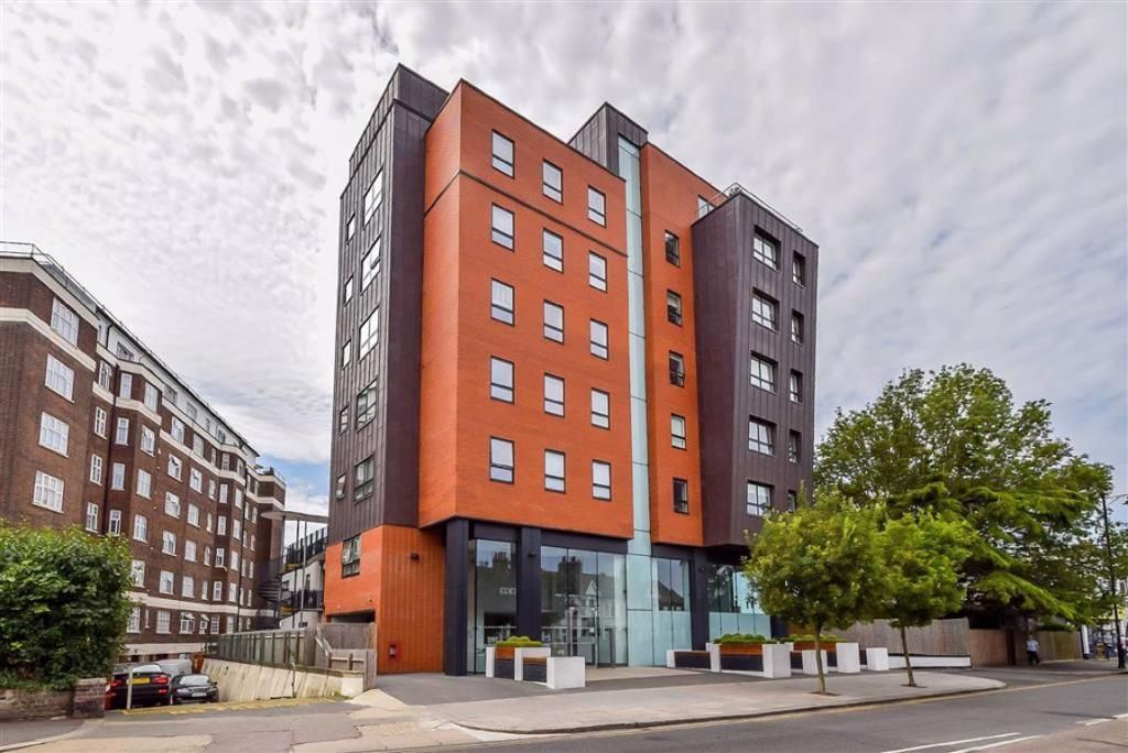 A large orange building with a lot of windows is sitting on the side of a street.