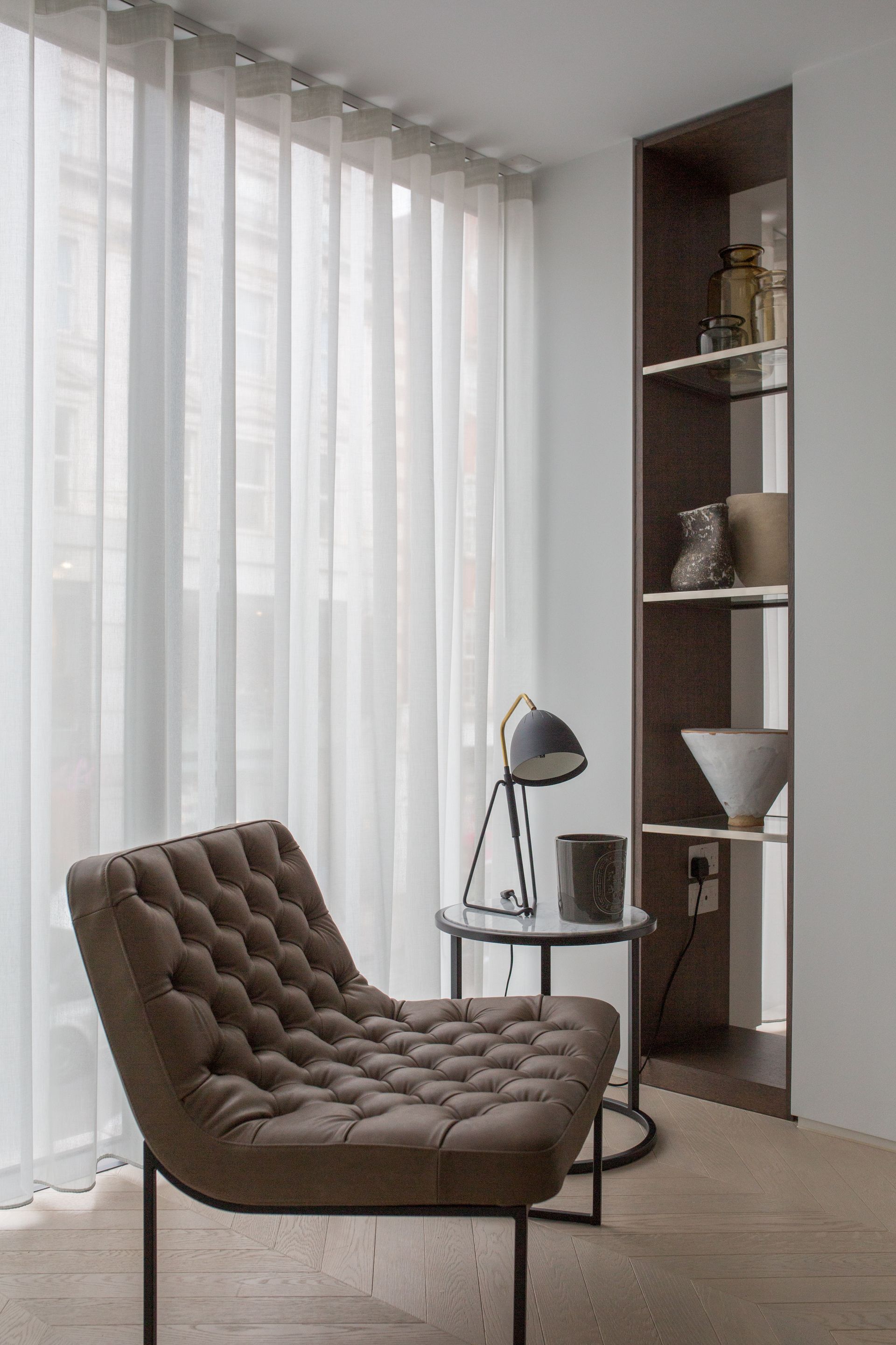 A chair is sitting in front of a window in a living room.