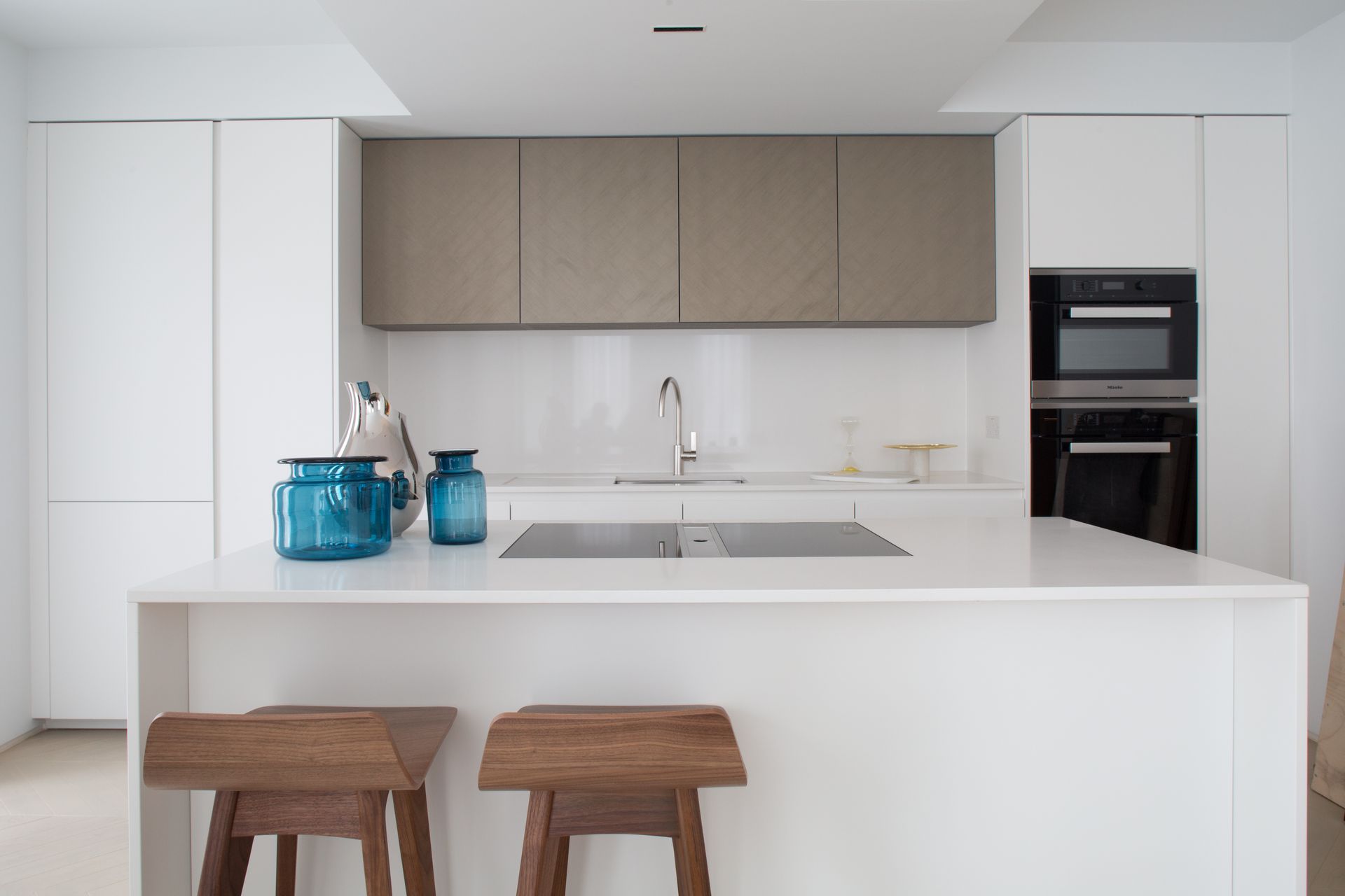A kitchen with white cabinets and wooden stools