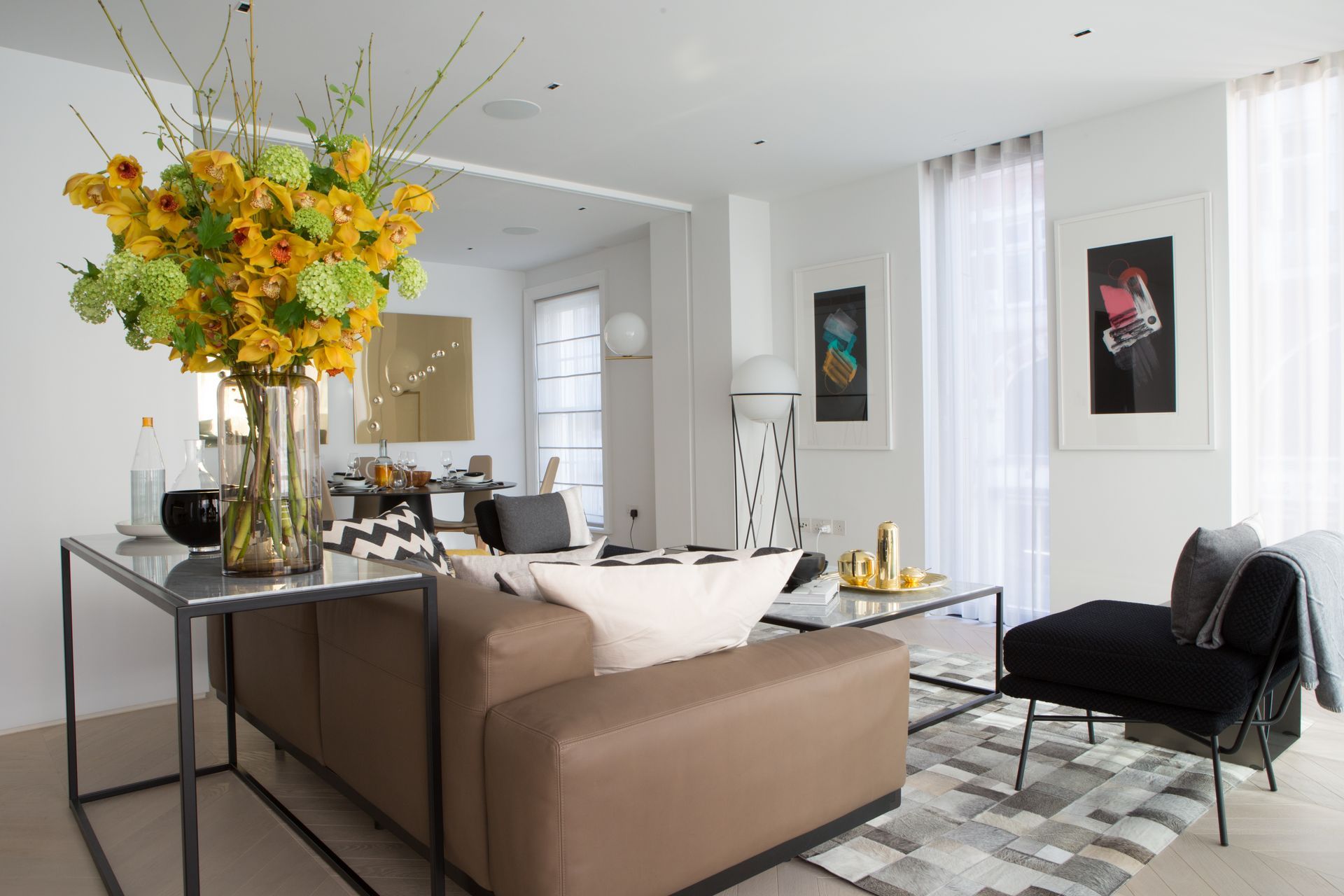 A living room with a couch , chair , table and vase of flowers.