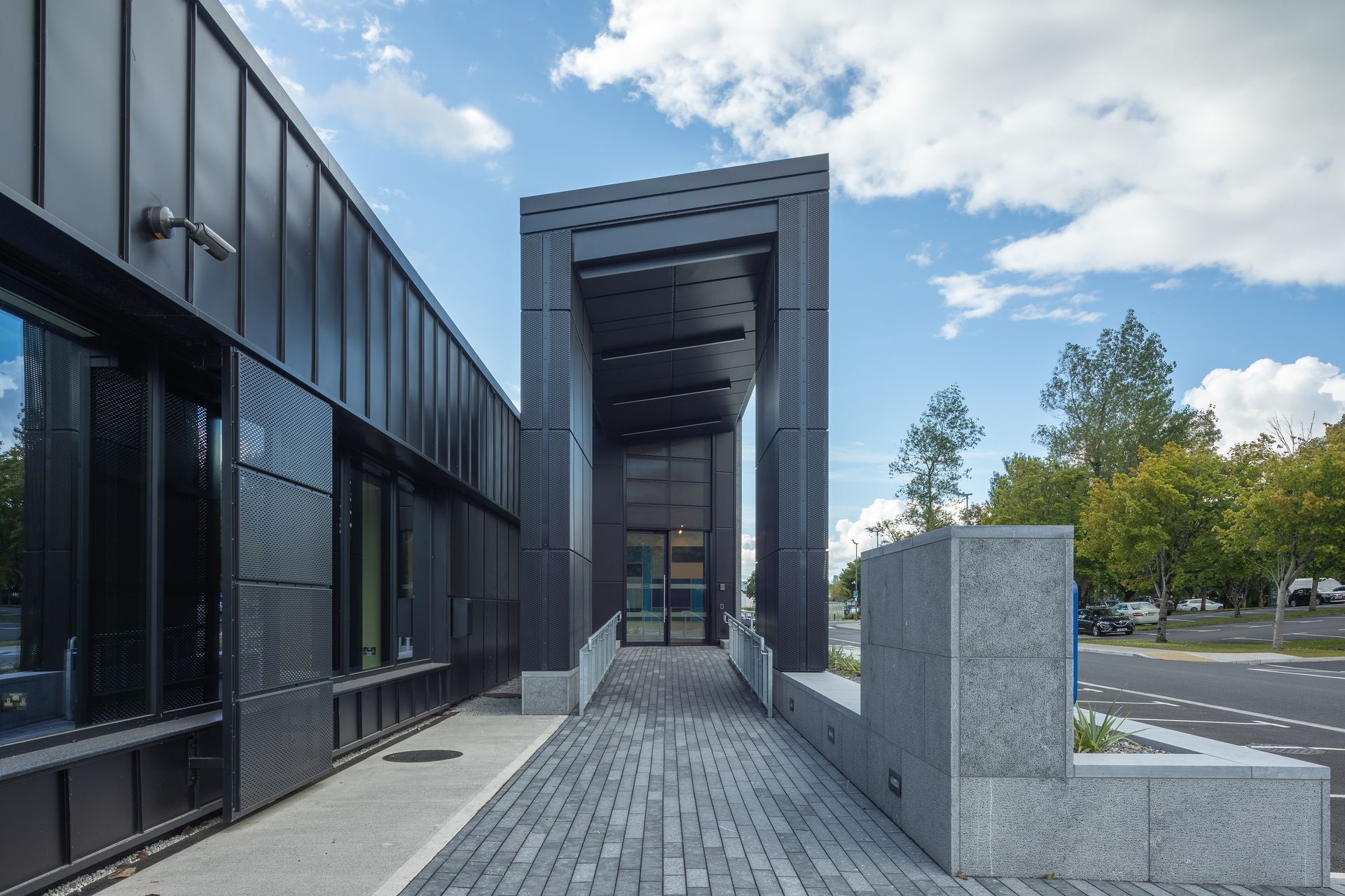 A black building with a brick walkway leading to it.