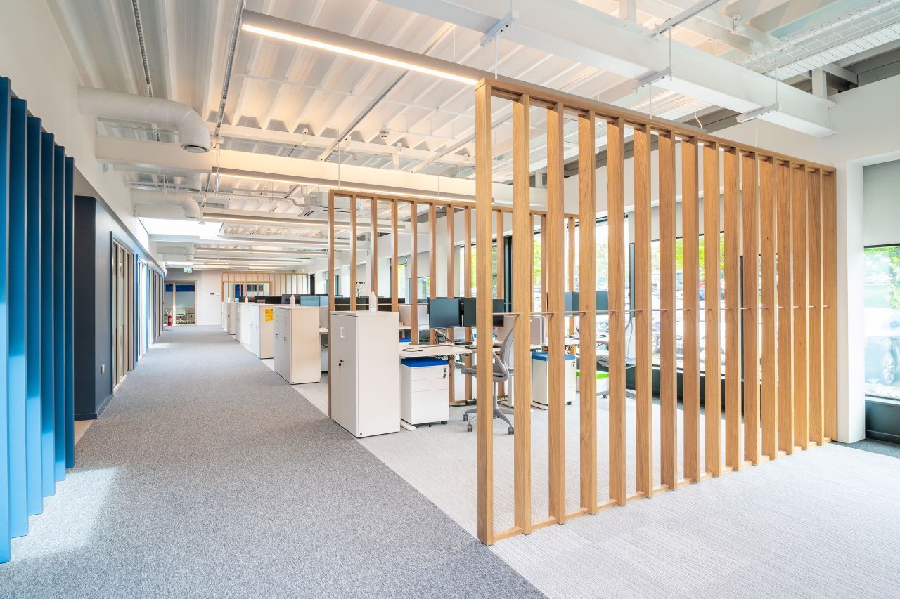 A large office with a wooden divider between the cubicles.
