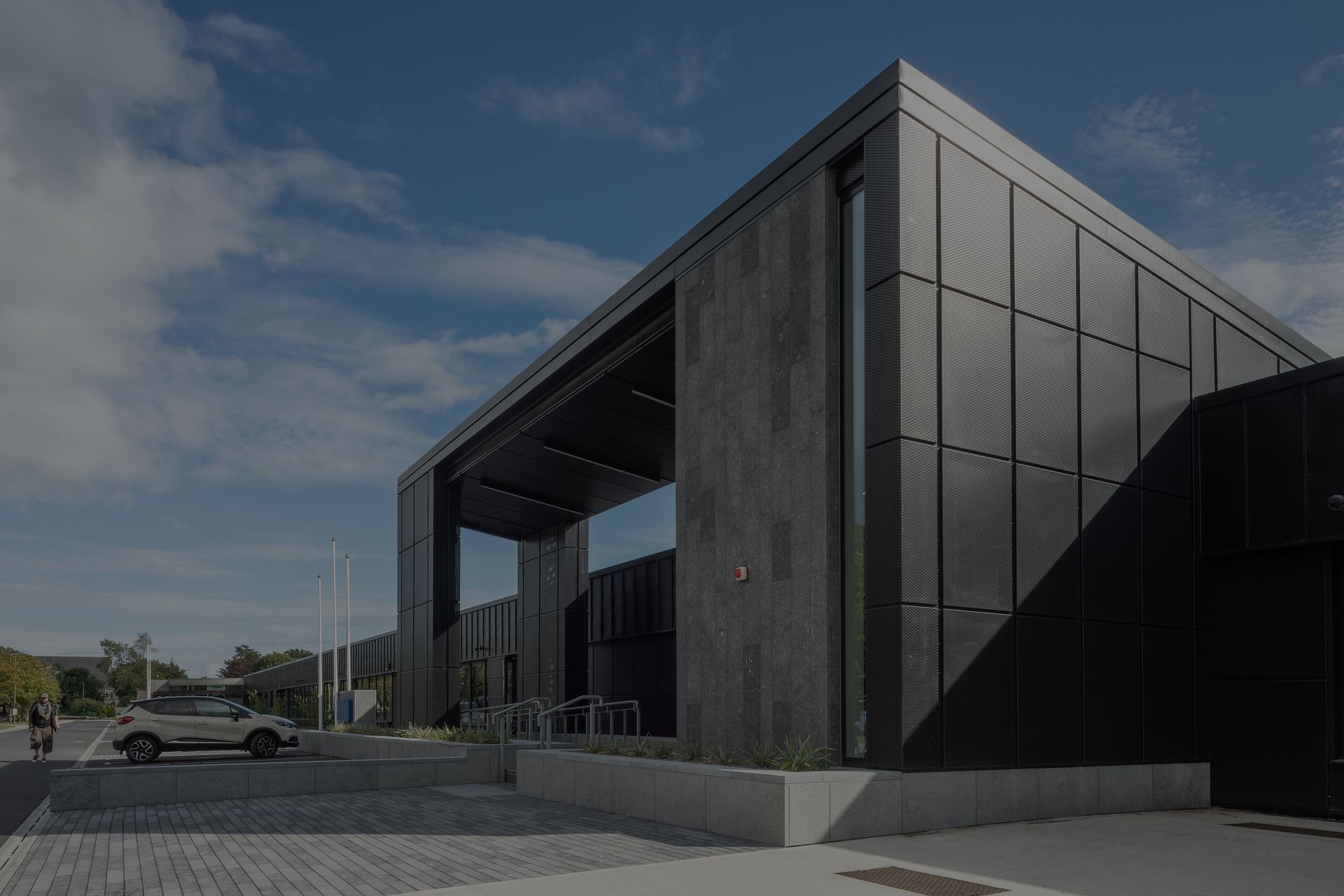 A black building with a car parked in front of it.