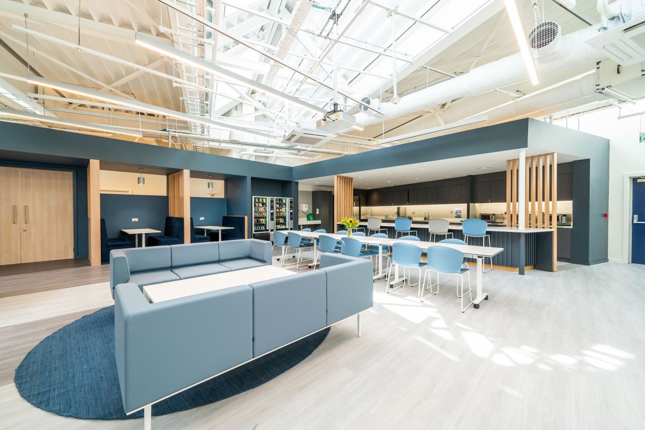 A large room with a couch , tables and chairs in it.