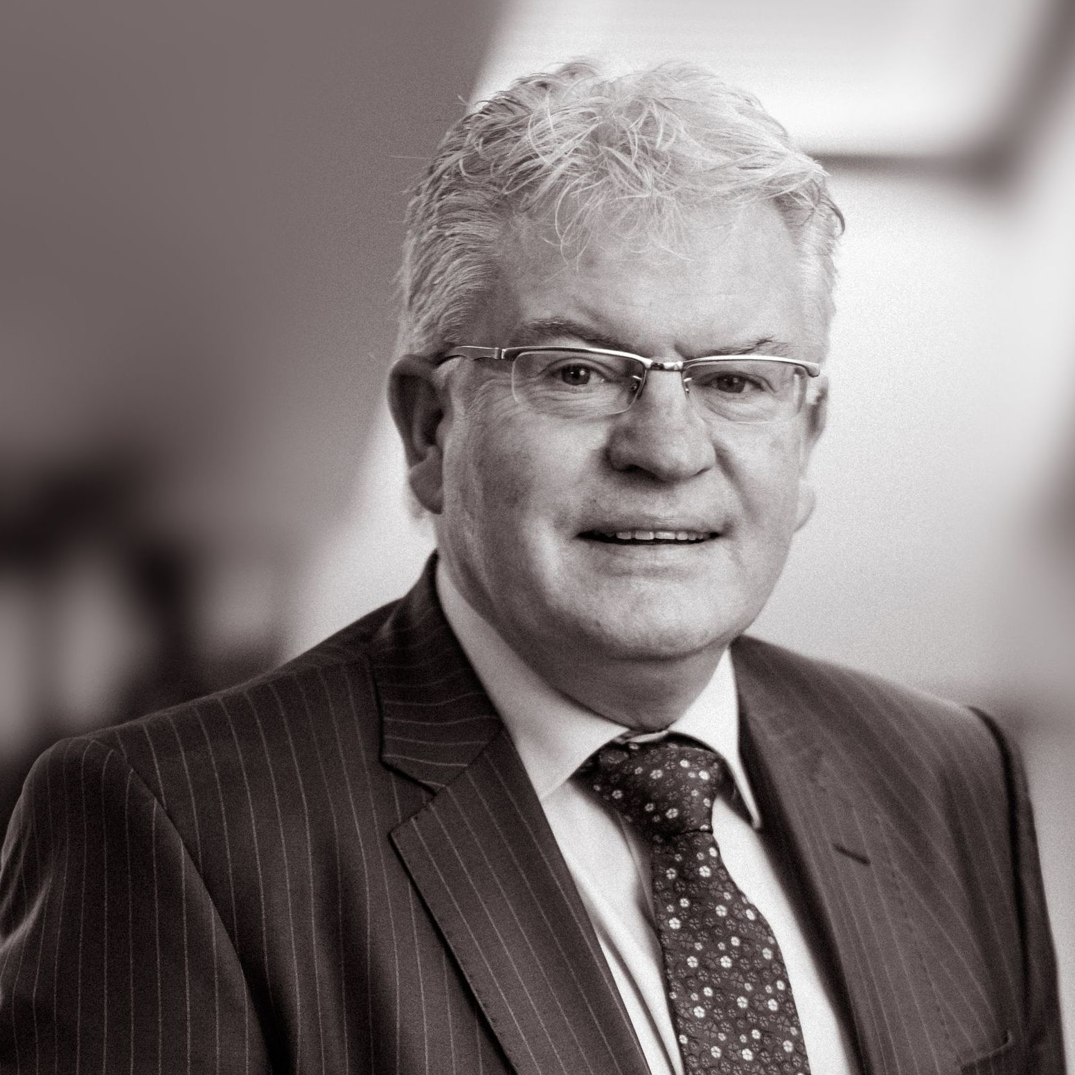 A man in a suit and tie is smiling in a black and white photo.