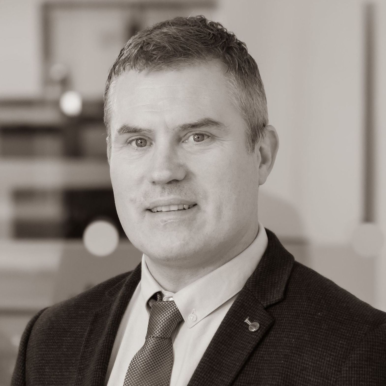 A man in a suit and tie is standing in front of a white background.