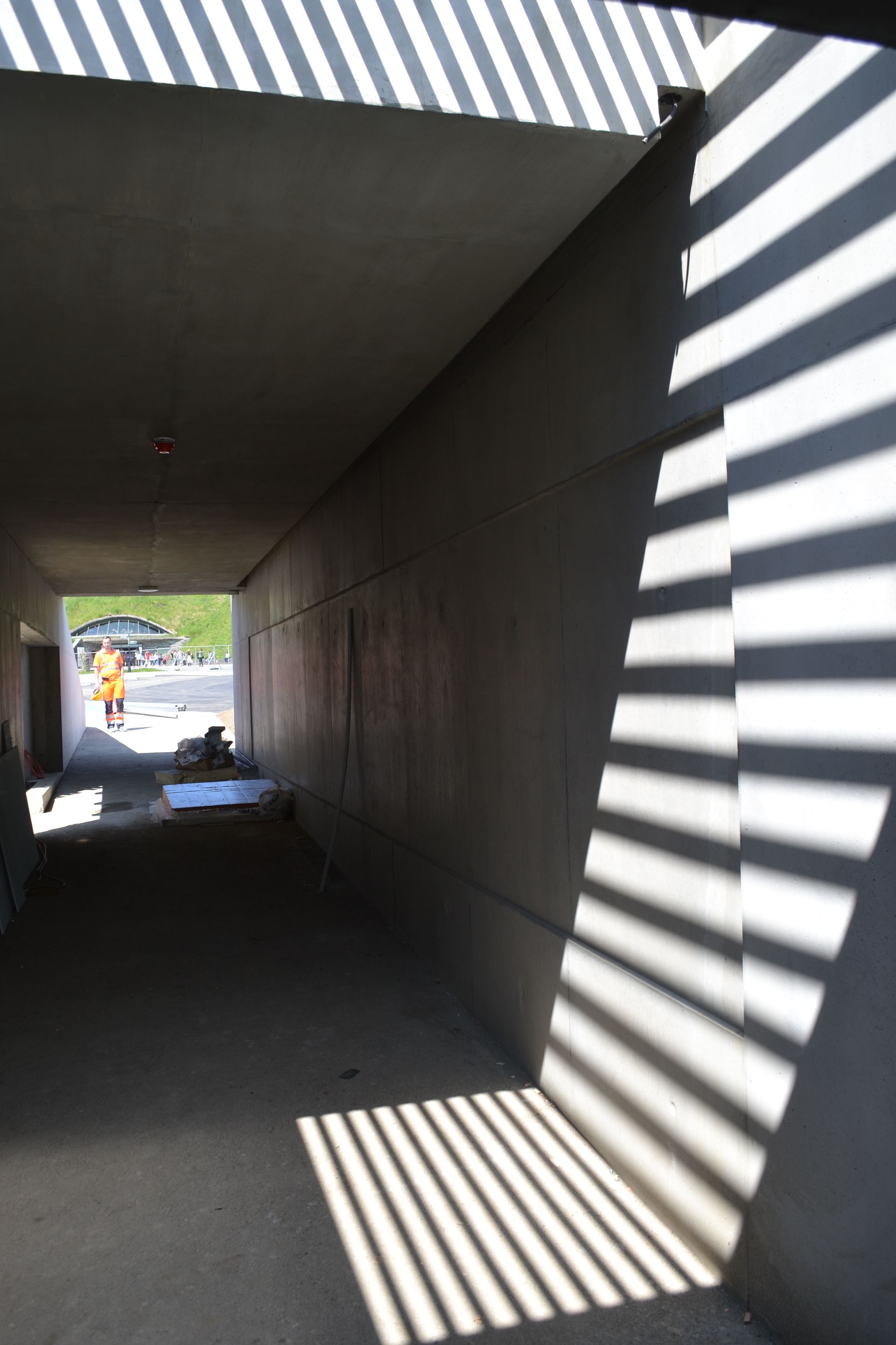 A shadow of a person is cast on a wall in a tunnel