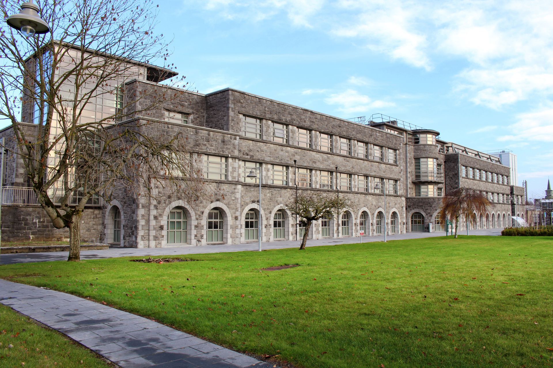 A large building with a lot of windows is surrounded by grass and trees.