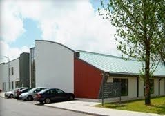 A row of cars are parked in front of a large building.