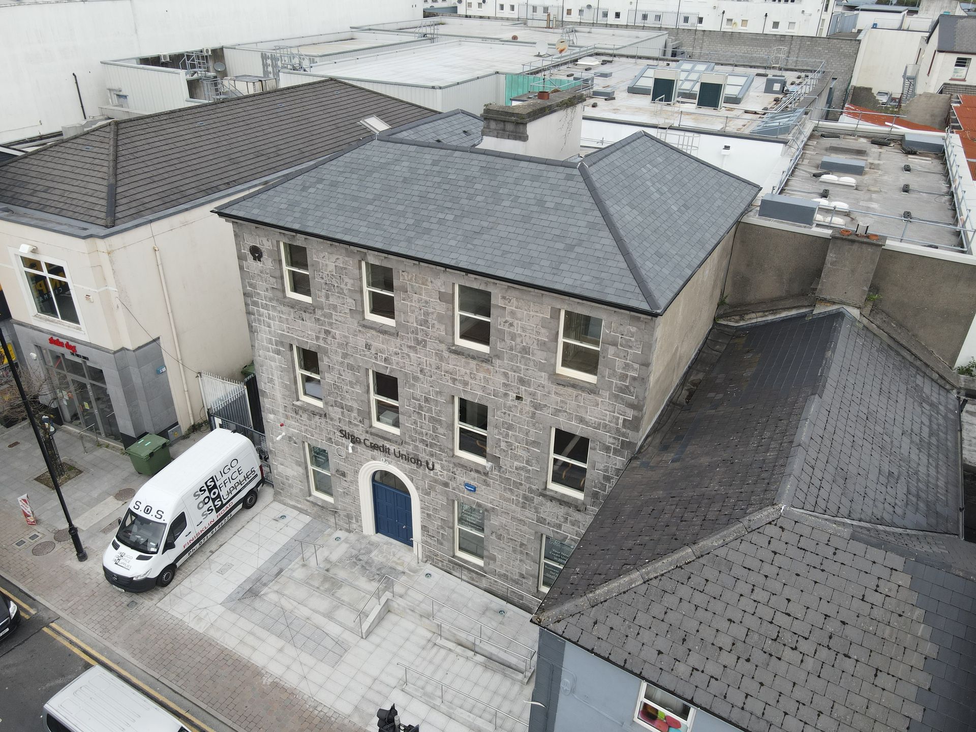 An aerial view of a building with a van parked in front of it
