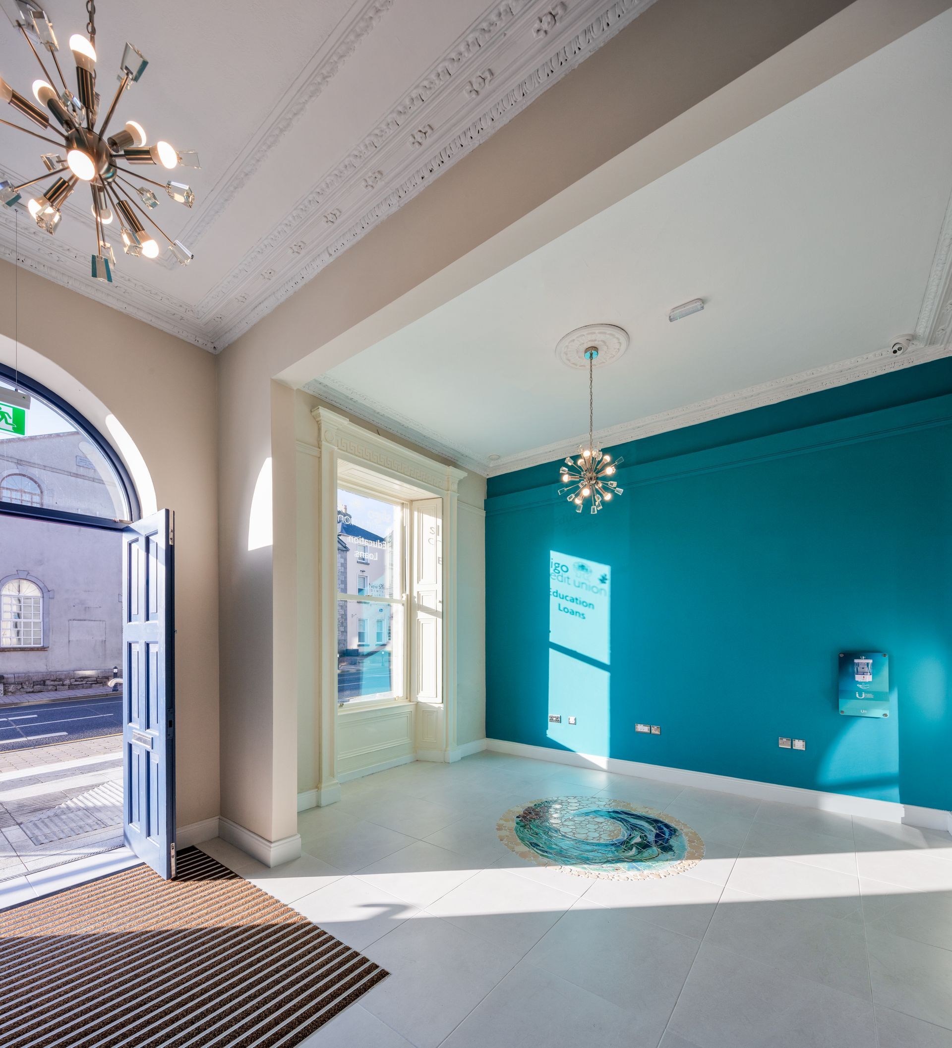 An empty room with a blue wall and a chandelier hanging from the ceiling