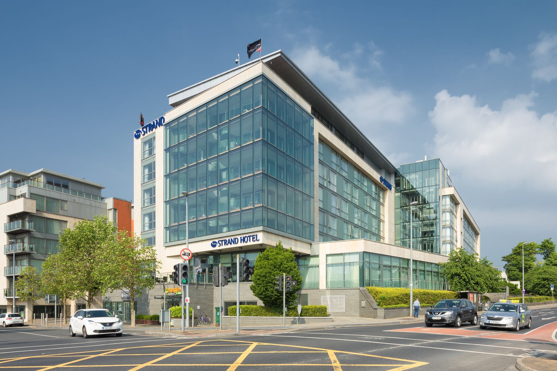 A large building with a lot of windows is sitting on the corner of a street.