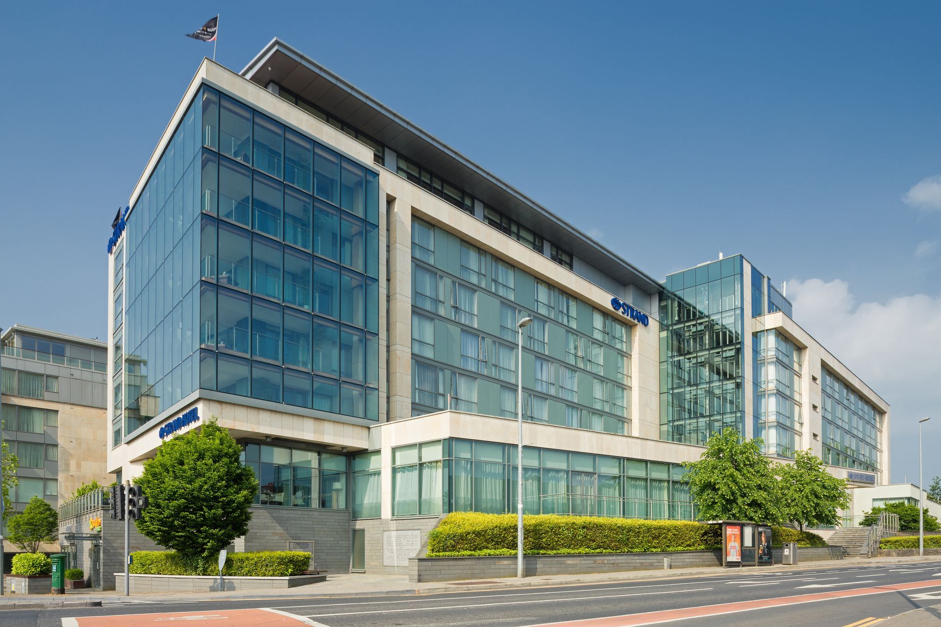 A large building with a lot of windows is sitting on the corner of a street.