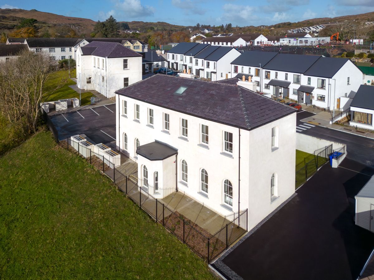 An aerial view of a white building with a fence around it