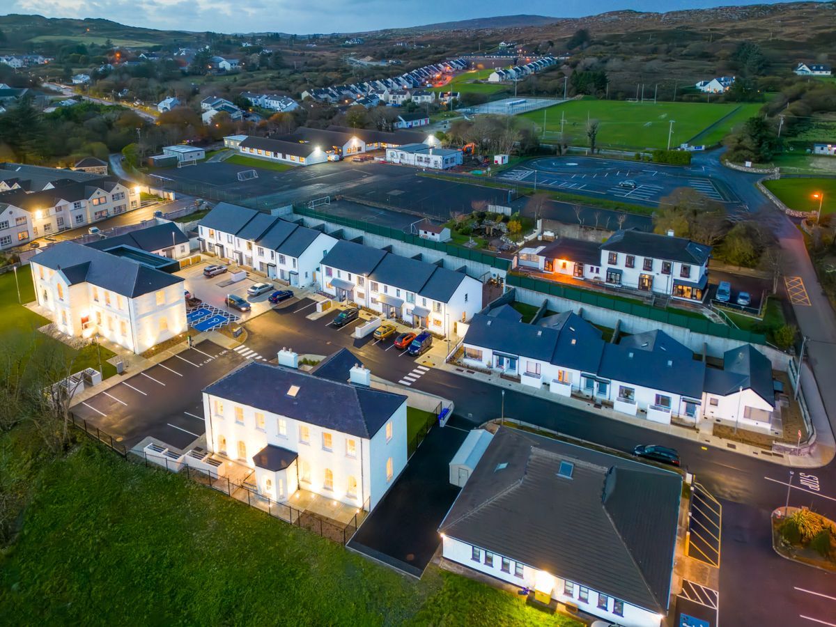 An aerial view of a row of houses and a parking lot at night.