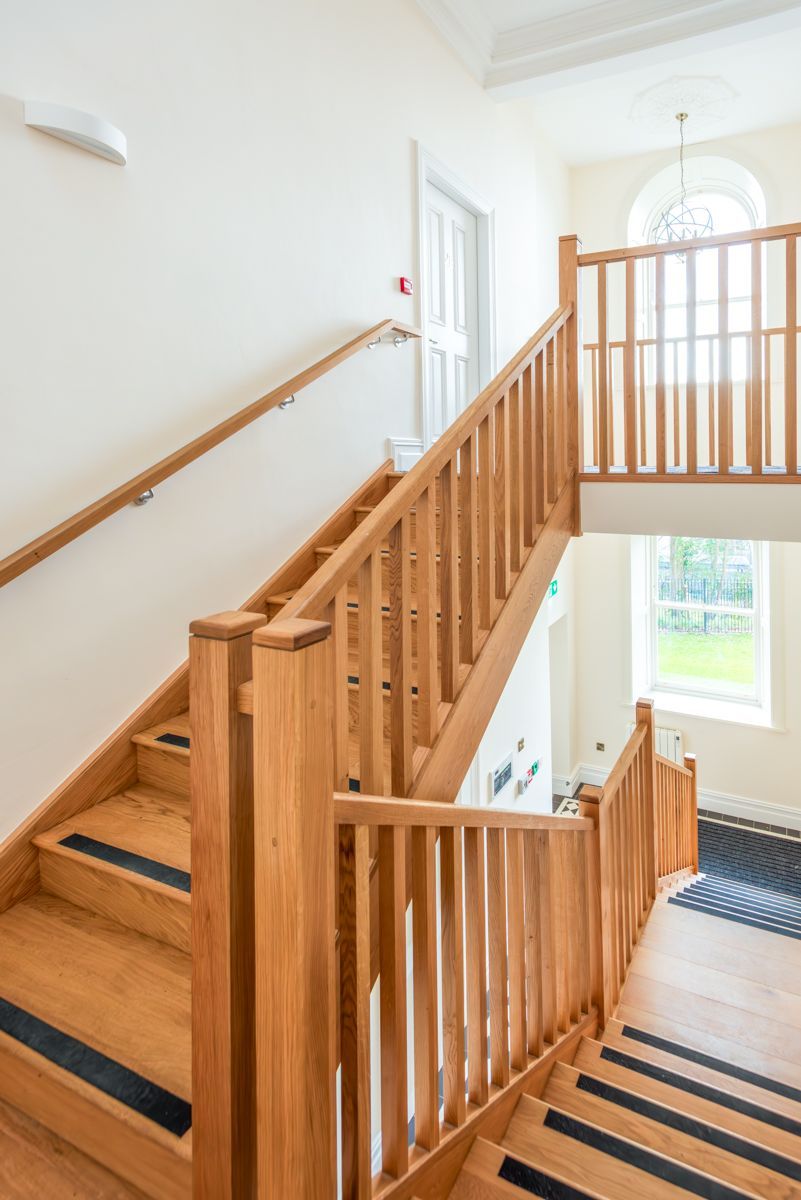 A wooden staircase with black steps and a wooden railing